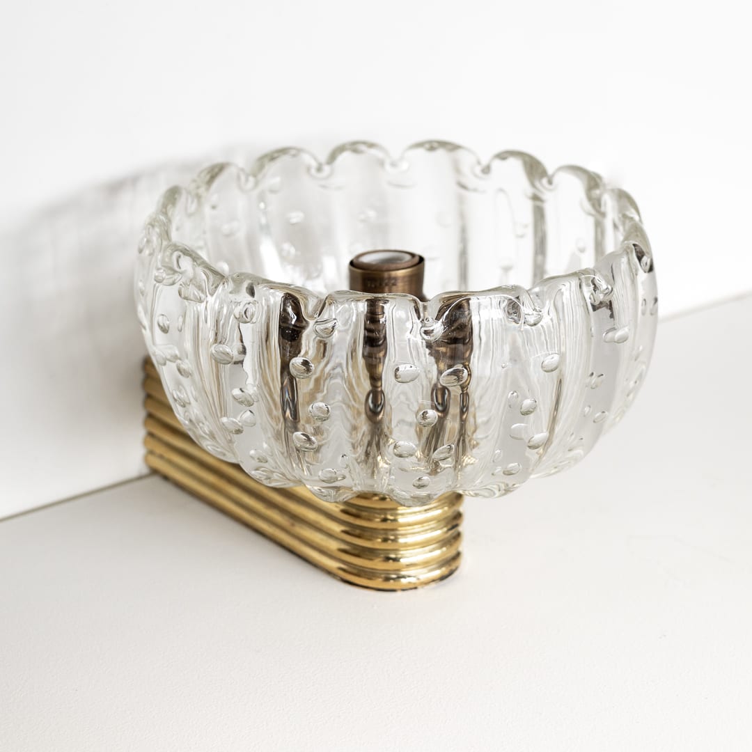 Stunning blown glass sconce from Italy, 1950's. Clear scalloped ribbed glass bowl shade with single socket. Original ribbed brass arm attaching to wall. Newly wired. Original backplate measures 1.75