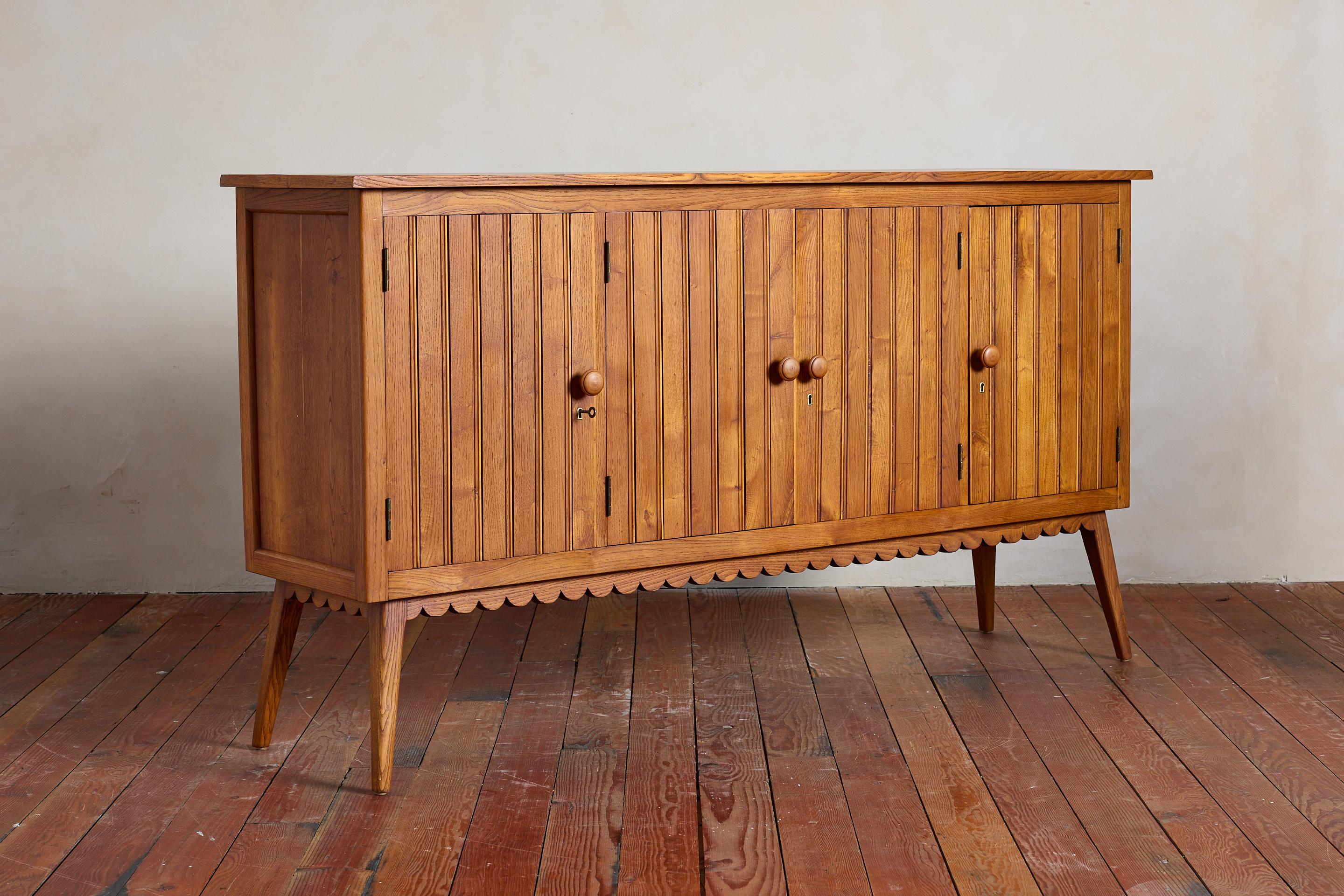 Precioso aparador italiano sencillo, Italia años 50 

Bonita y cálida pátina de roble con puertas batientes de textura 4x y pomos de madera

Intrincados detalles festoneados a lo largo de la parte inferior con patas angulosas.
