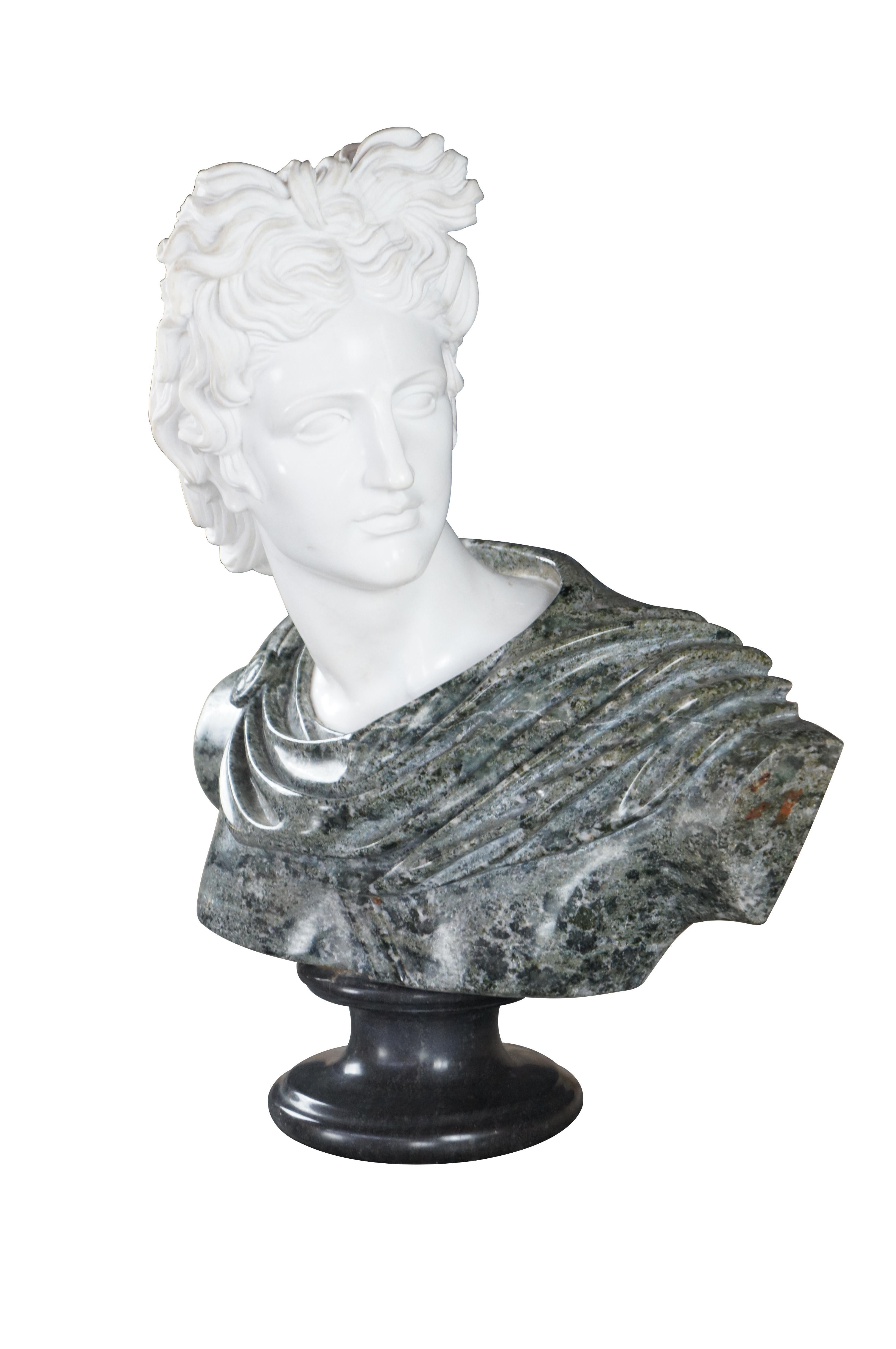 A carved two-toned marble bust depicting the image of Apollo with draped garb details. Mounted to a round tapered marble plinth. circa 20th century. Very heavy and stately. Made in Italy. Perfect for display on a table, bookcase or stand. 

Apollo