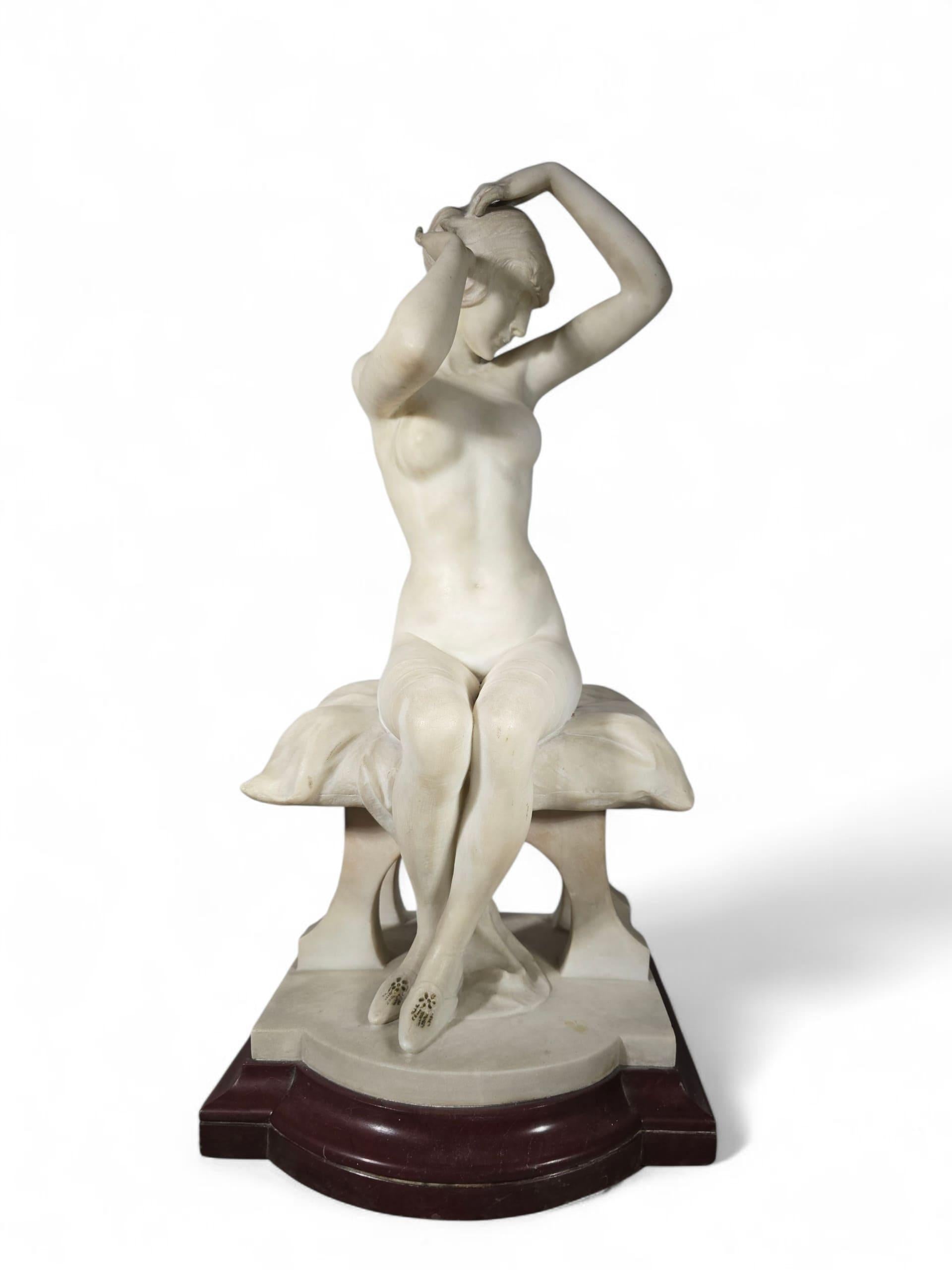 Scuola italiana, primo quarto del XX secolo.
Scultura in marmo bianco intagliato che raffigura una giovane donna nuda seduta su un cuscino che si raccoglie delicatamente i capelli. L'opera poggia su una base di marmo Rouge Griotte.
Dimensioni: