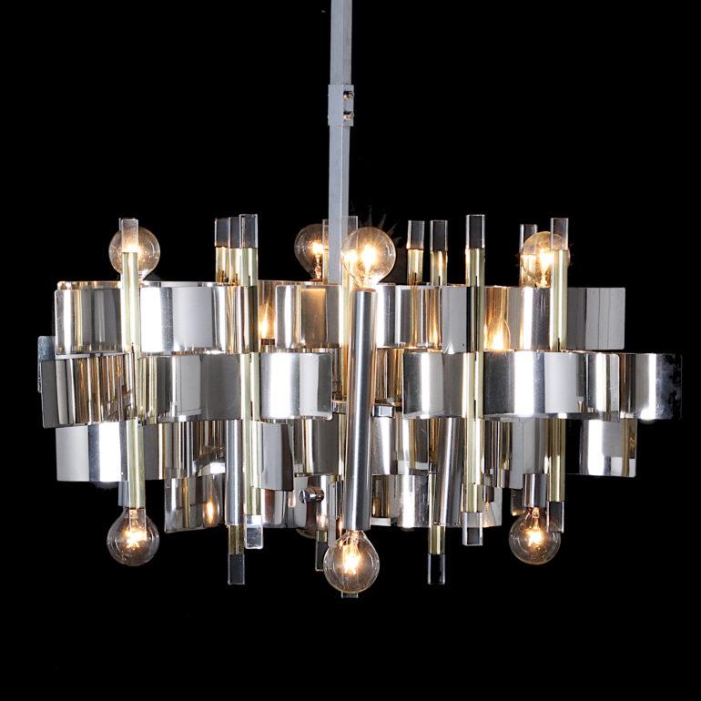 Unusual Italian chrome and Lucite chandelier designed by Gaetano Sciolari, the body comprised of interlocking chrome half-round pieces with chrome and gilt uprights. Twelve bulbs in total.