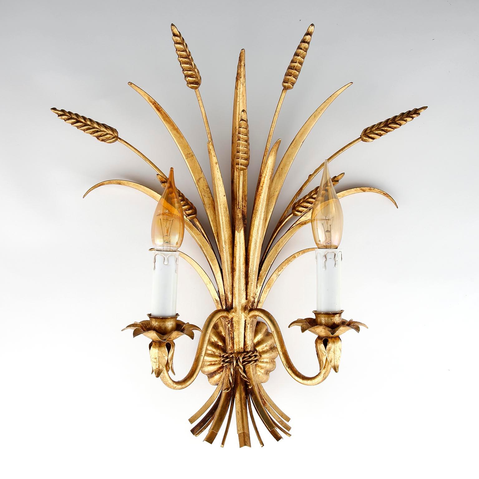 A pair of Hollywood Regency wall light fixtures from Italy manufactured in midcentury, circa 1970 (1960s-1970s). The lights are in the form of a bunch of wheat sheafs and they are made of antique leaf gold plated metal. Each lamp has two sockets for