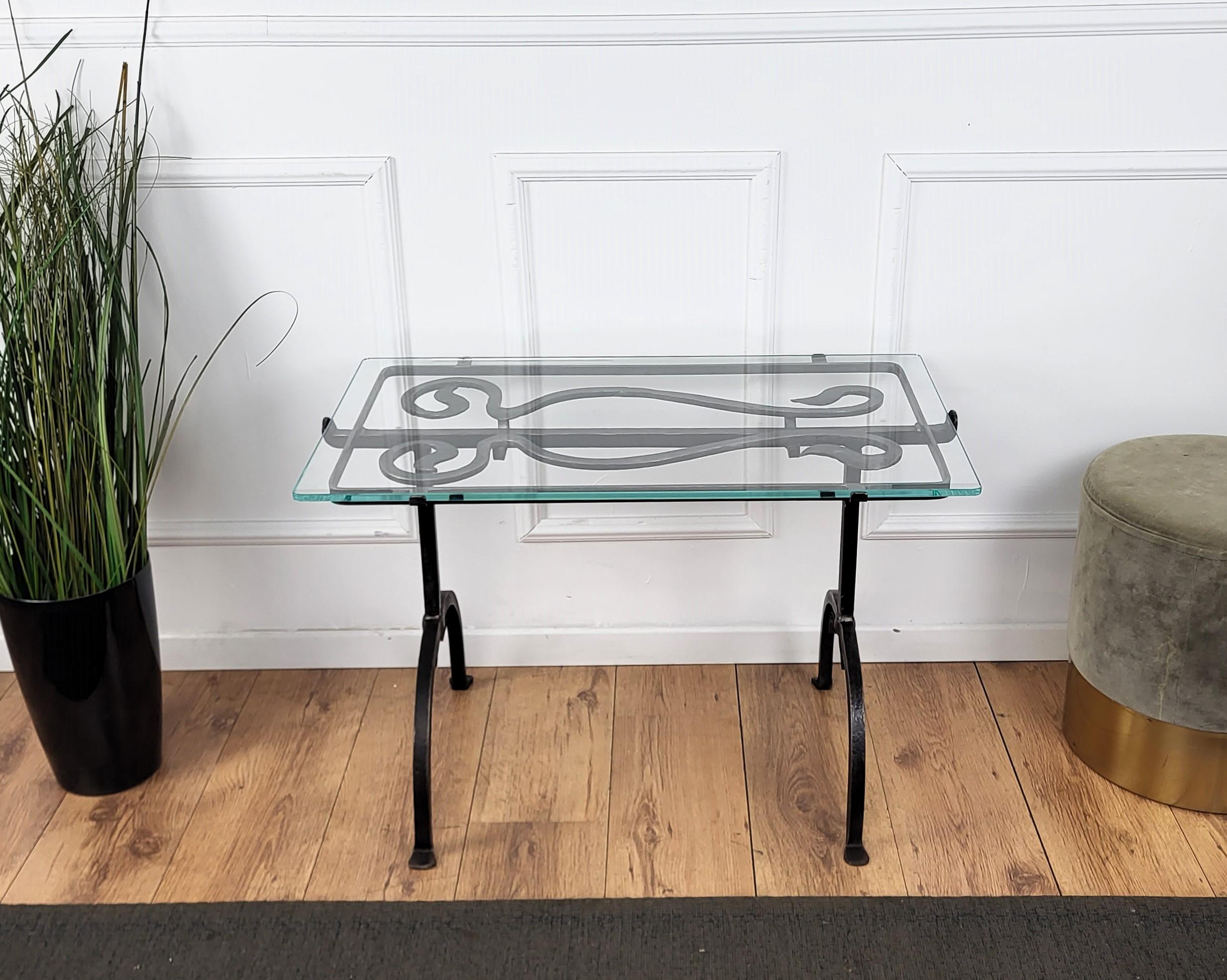 Beautifully hand crafted wrought iron side table with strong and thick glass top, placed on a decorative frame. The legs, greatly shaped and forged with the typical finish of hand forging, are finished with round feet and centrlly united with