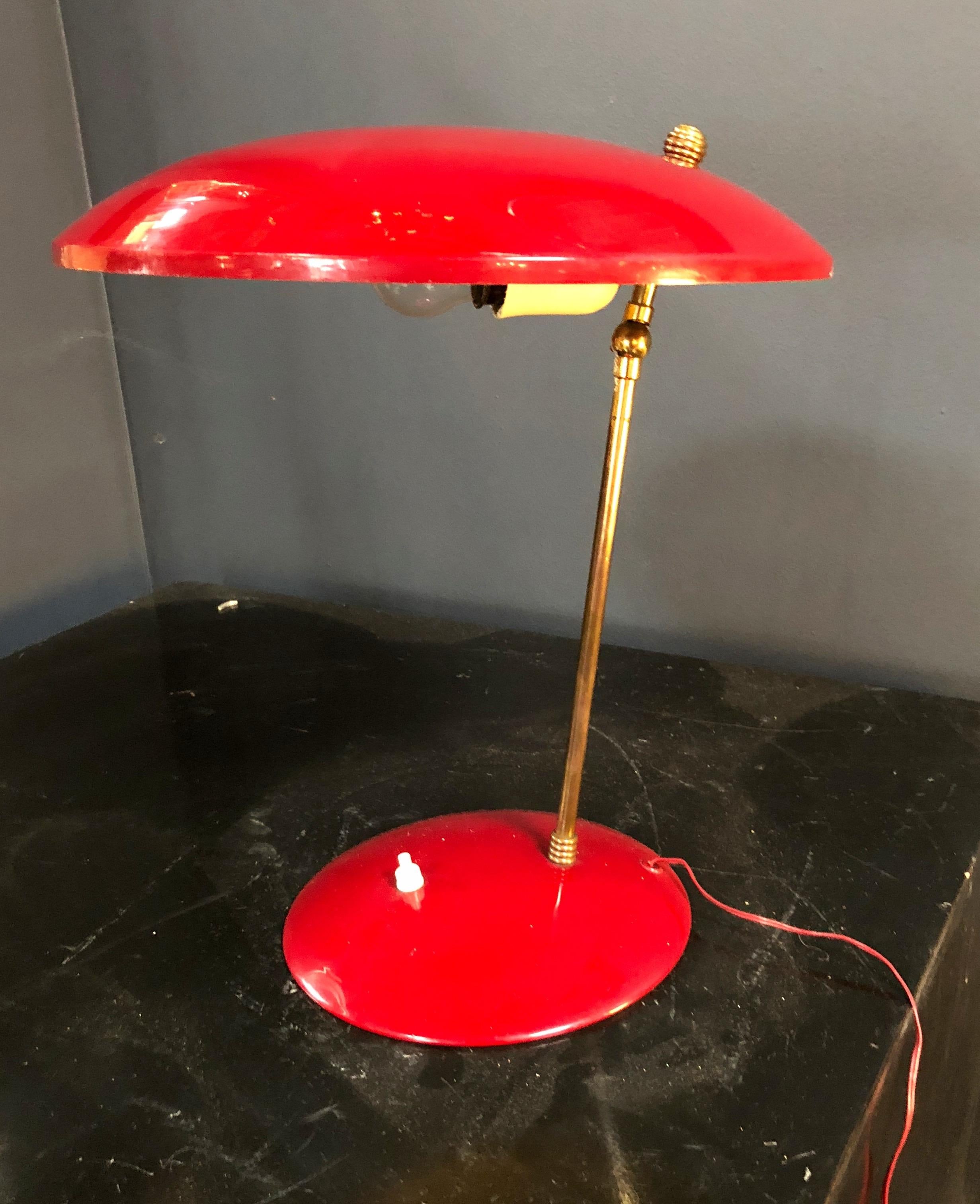 An Italian sculptural table lamp in red enameled metal in the style of Stilnovo. The domed shade is adjustable.