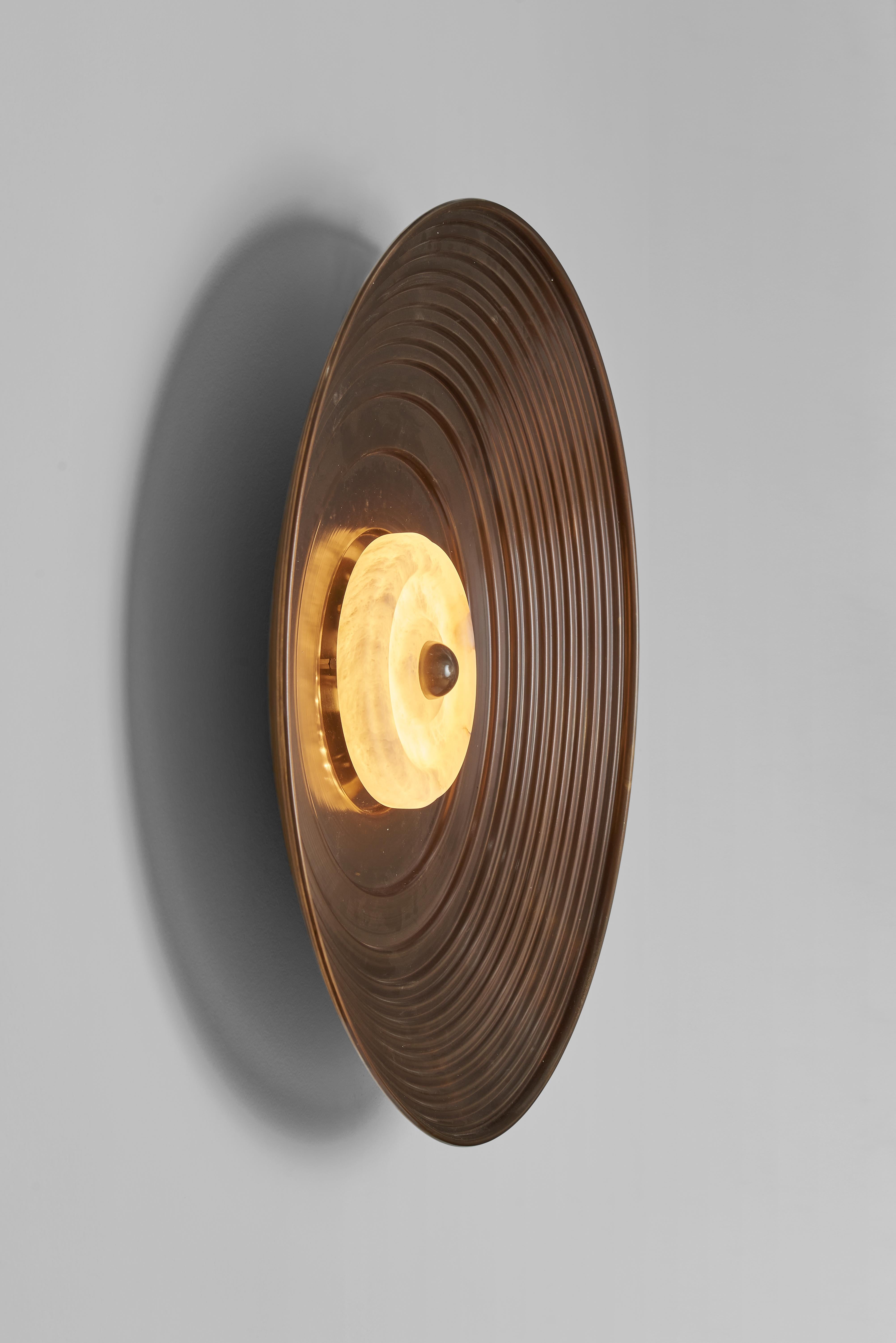 A wall sconce created in collaboration with the milanese interior design studio LC Atelier.
This lighting fixture features a concave disc made from burnished brass sheet that has been turned by hand. The disc is characterized by concentric circles