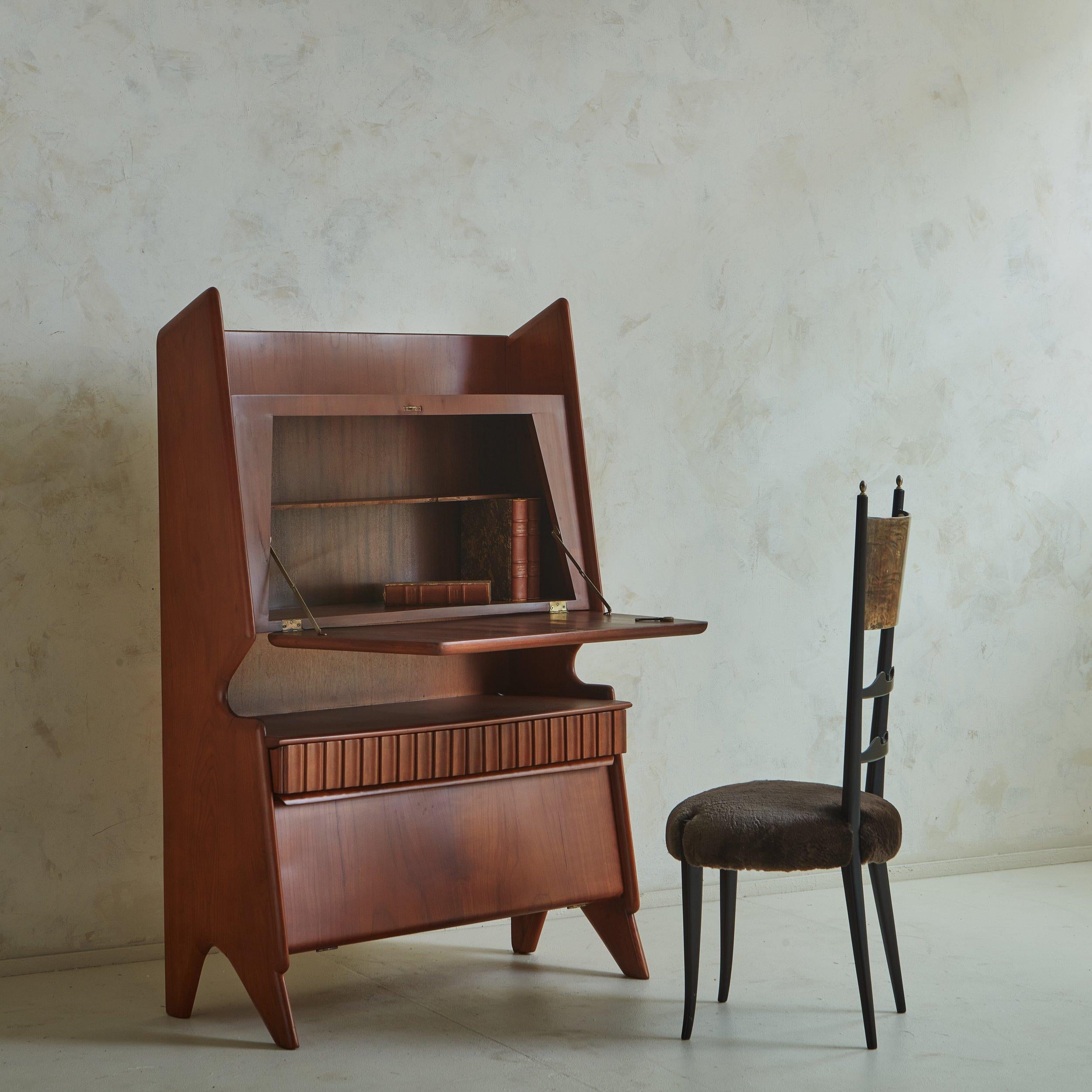 A stunning 1950s Italian secretary desk constructed with birch and walnut. This piece features a sculptural profile with a channeled trim detail and angled, tapered legs. A uniquely shaped drop front writing surface opens with a key to reveal one