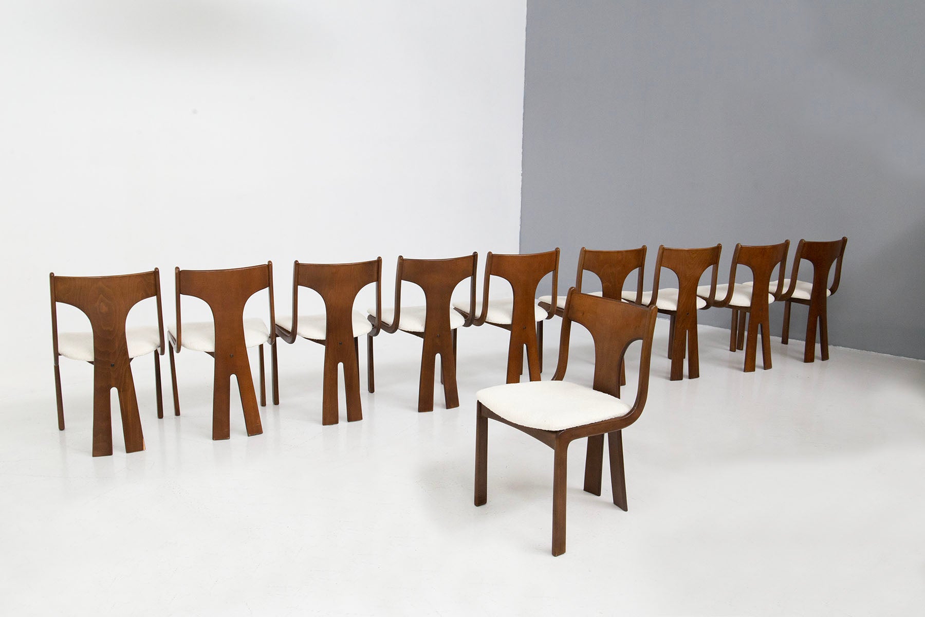 Eccentric and elegant set of ten chairs of Italian manufacture from the 1950s. The set consists of 10 chairs. Their greatest peculiarity is in the back of each seat, in fact it denotes a sculptural as well as geometric design. The lines of the back