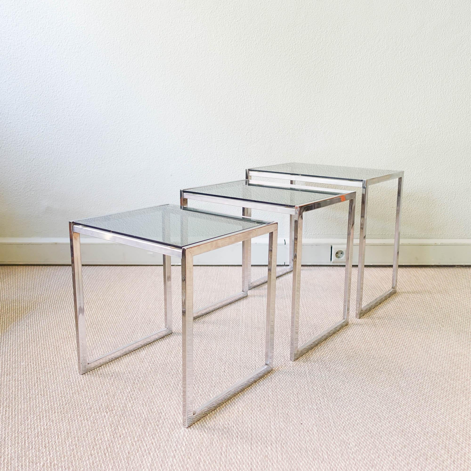 This set of three nesting tables was designed and produced during the 1970's in Italy. With a very clean design they are made of chrome metal with glass tops. In original and good condition, with a small chip in one of the glasses. 
Dimensions:
