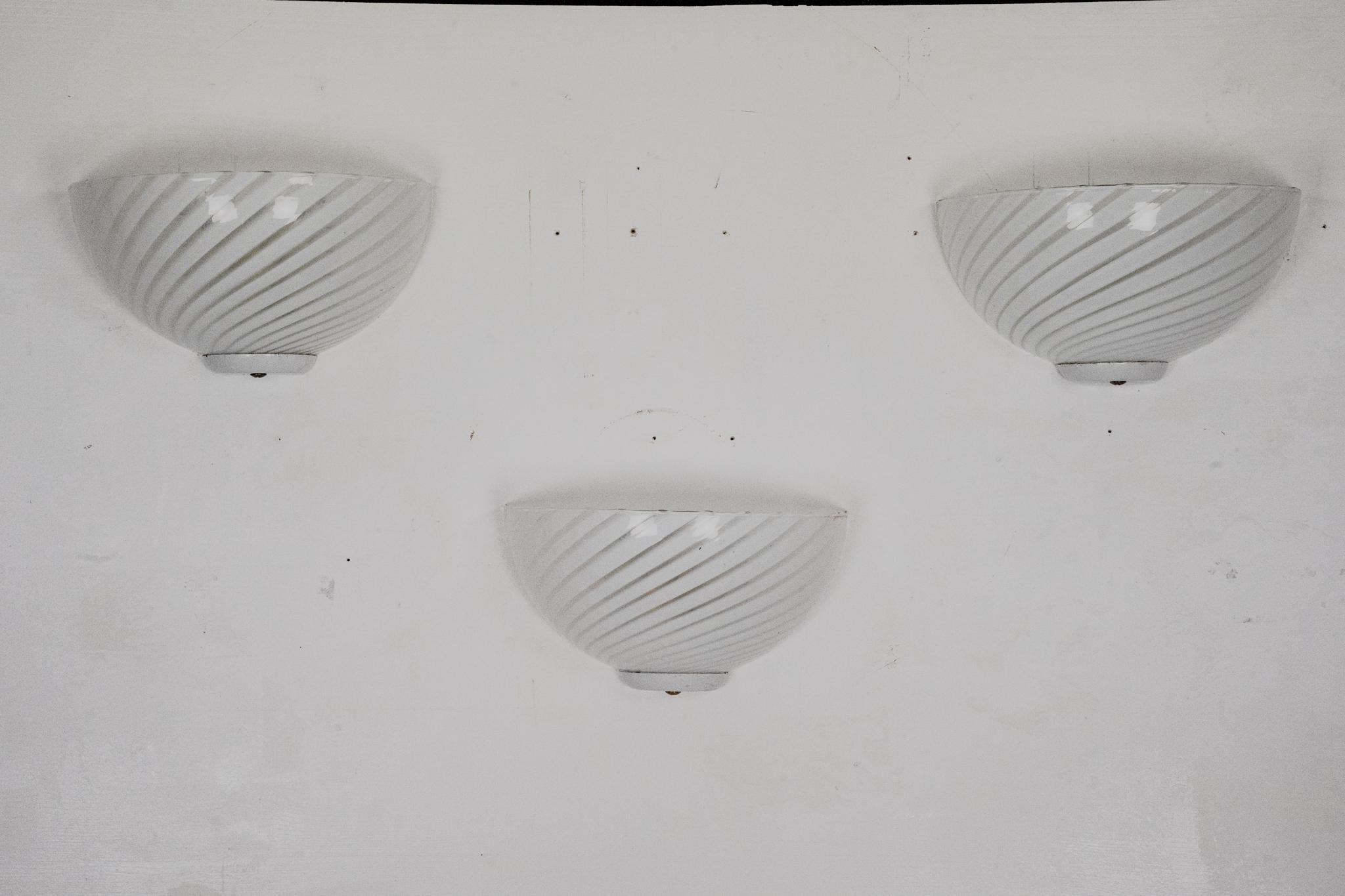 Uno splendido set di tre appliques in vetro di Murano, realizzate in Italia negli anni '70 nel caratteristico stile Venini. Ogni applique è caratterizzata da un vetro di Murano a righe che crea un raffinato gioco di luci e texture, completato da