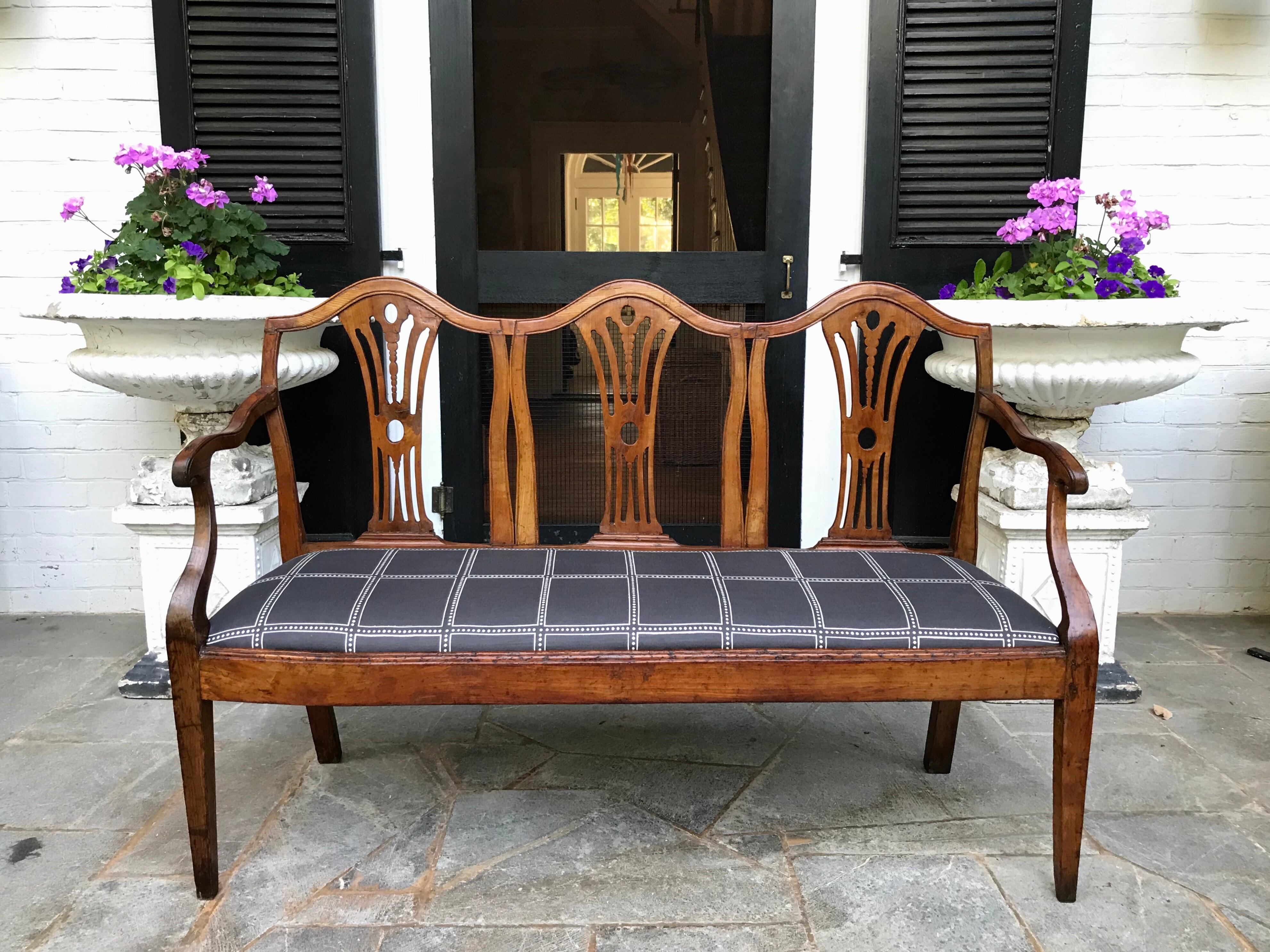 A sleek 19th century Italian triple backed hall bench of walnut and fruitwood dressed up for success in 