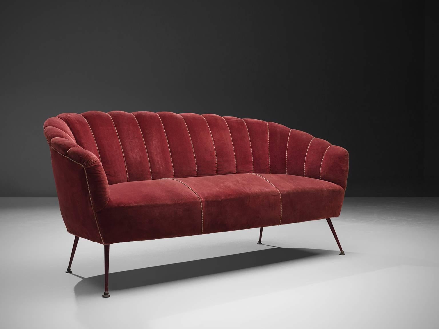 Settee attributed to ISA, red velvet and wood, Italy, 1950s. 

This ornate, cute but grand sofa is strong and playful at the same time. The webbed back gives perfect support for the sitter. The delicate wooden legs support the voluptuous seat,