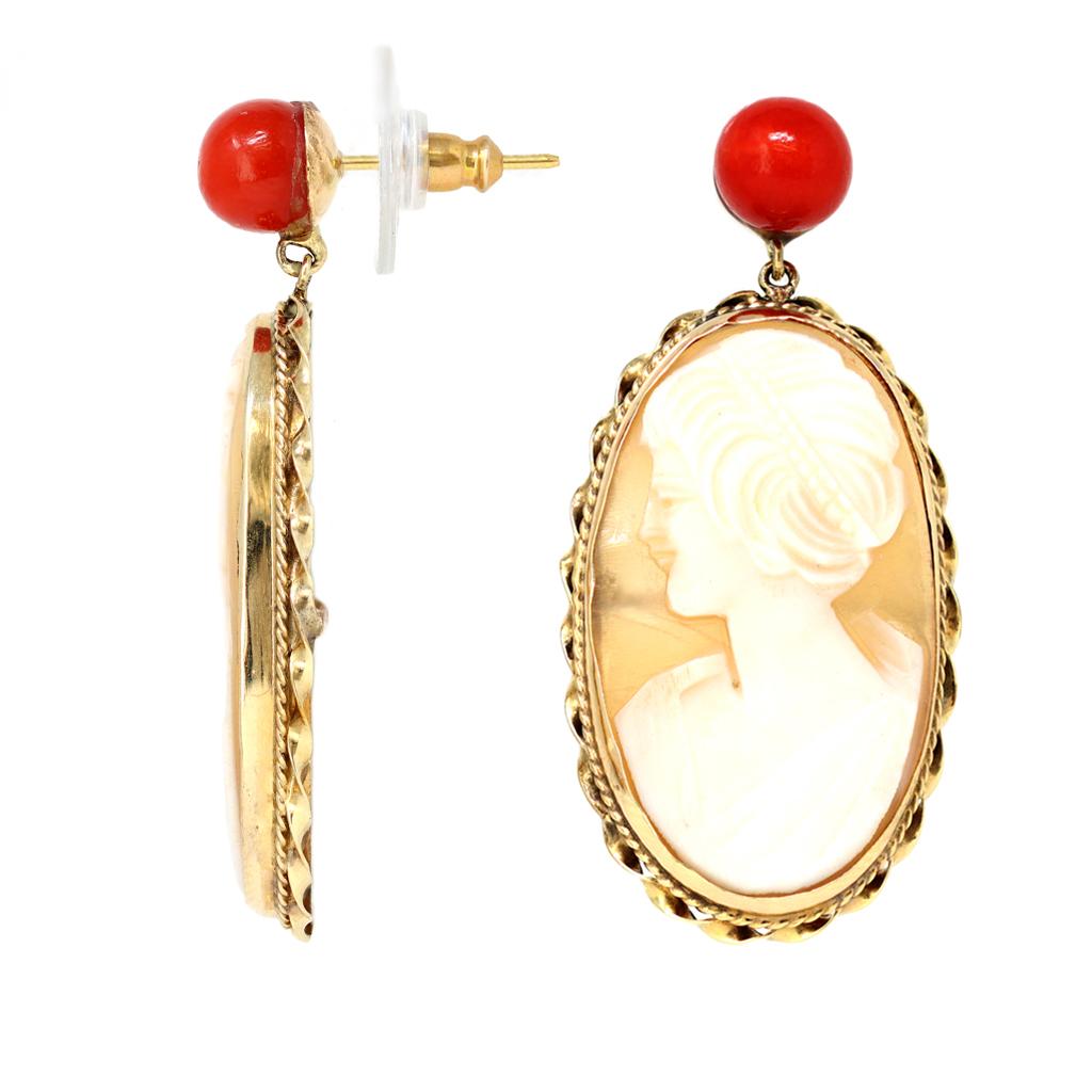 A pair of vintage cameo shell dangling earrings with Mediterranean deep red coral bead stud. Originated in Italy circa 1920-30, the earrings are composed of a red coral bead stud and a cameo pendant representing a female figure set in a handmade