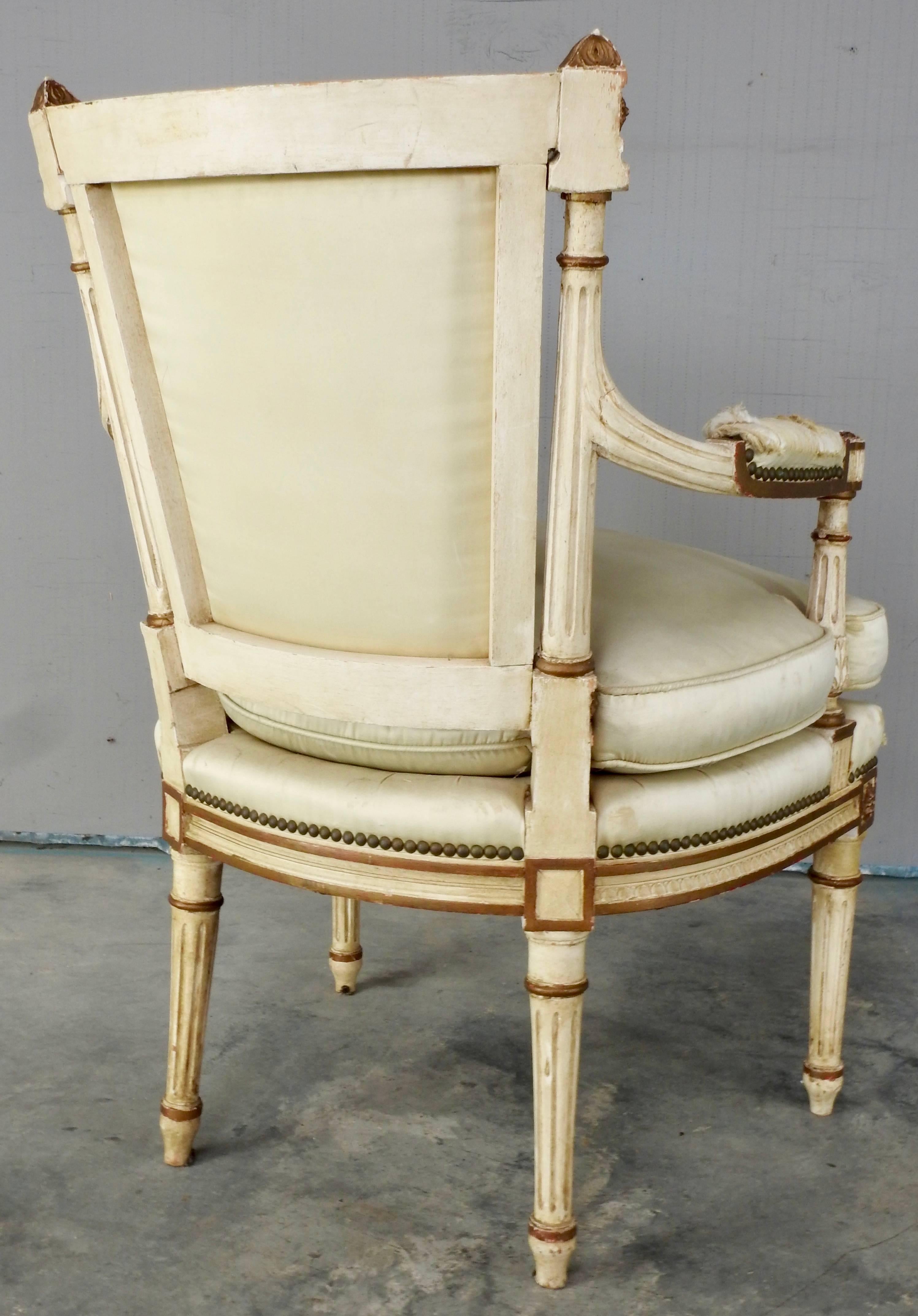 This is a stunning hand painted cream and gold painted Sheraton armchair. Aged satin covers the seat and back. The seat has a down filled filler. The arm rests are padded and covered in satin that is distressed. The hand-carving is intricate with