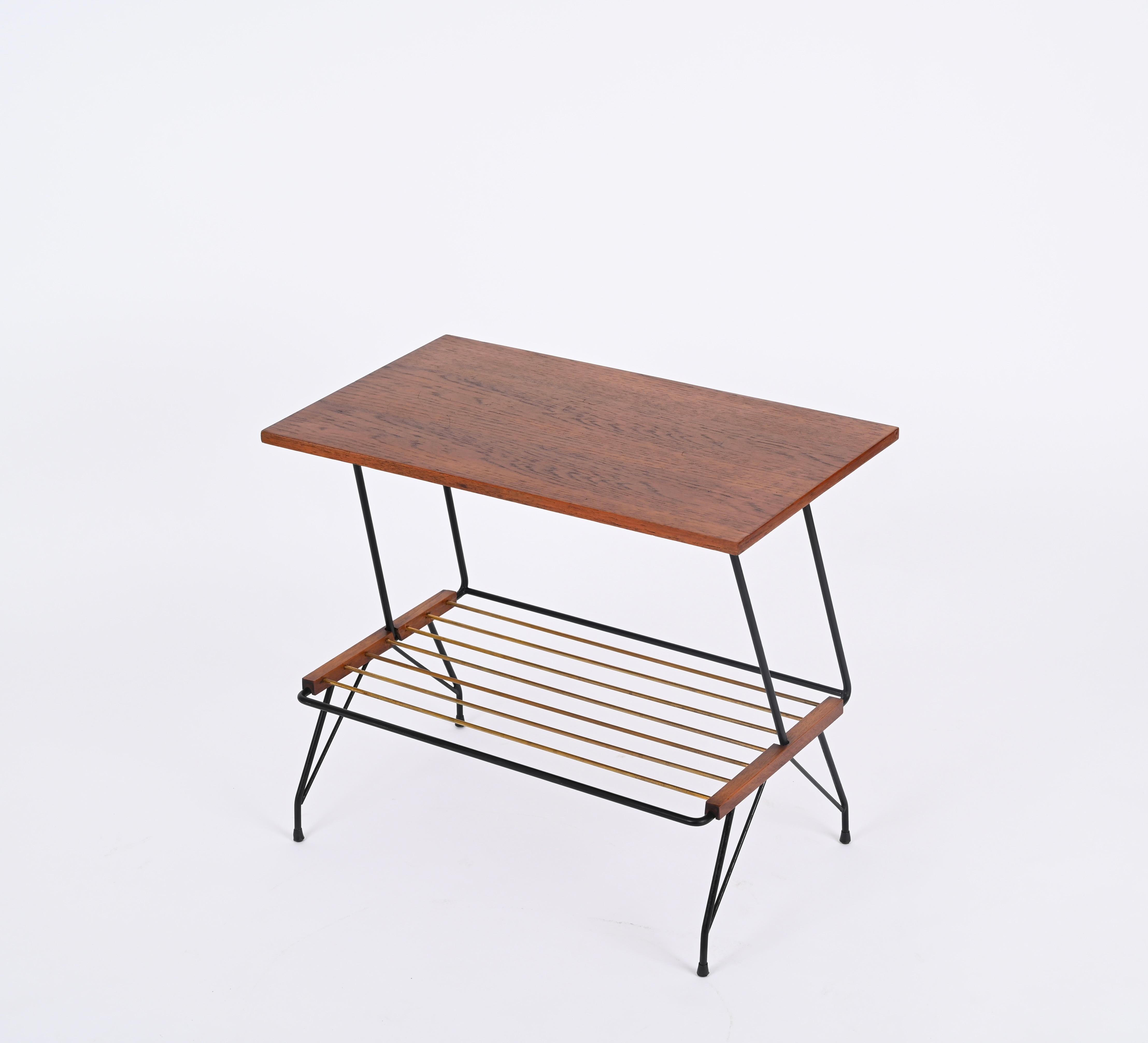 Wonderful Mid-Century coffee or side table in walnut wood, enameled black metal and brass magazine rack.  wooden, brass and black metal coffee table. This elegant small table was designed in Italy during the 1950s by Mobili Pizzetti Roma.

The side