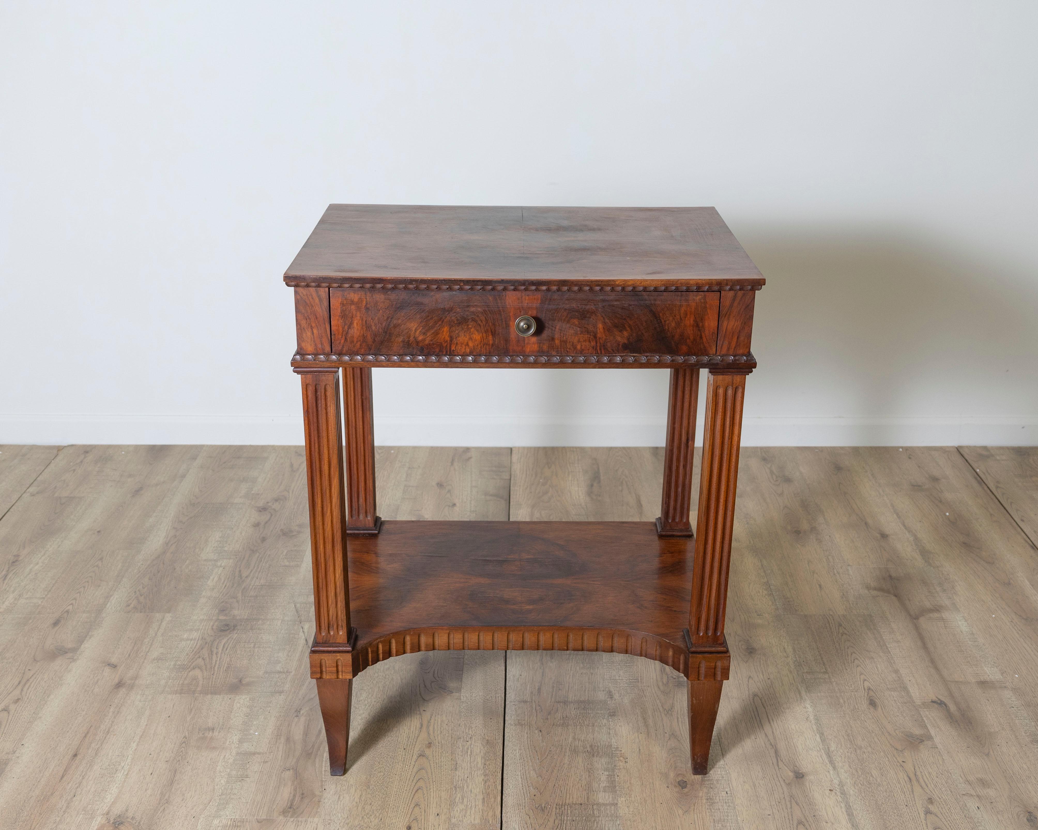 Elegant and finely crafted, this Italian side table from the early 19th century showcases the refined neoclassical sensibility of the period. Made of richly grained walnut, the table features a single drawer adorned with a brass knob and framed by a