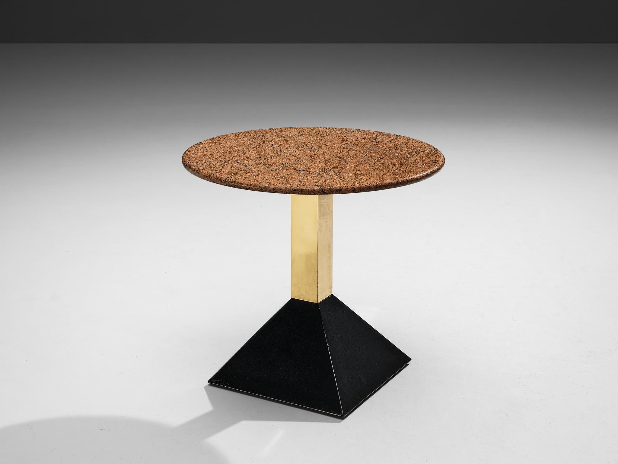 Table d'appoint, granit, métal, laiton, Italie, années 1980

Cette table d'appoint présente un plateau en granit rouge de format rond. Le granit présente une surface vive. Un socle en laiton se termine par une base trapézoïdale noire en métal. La