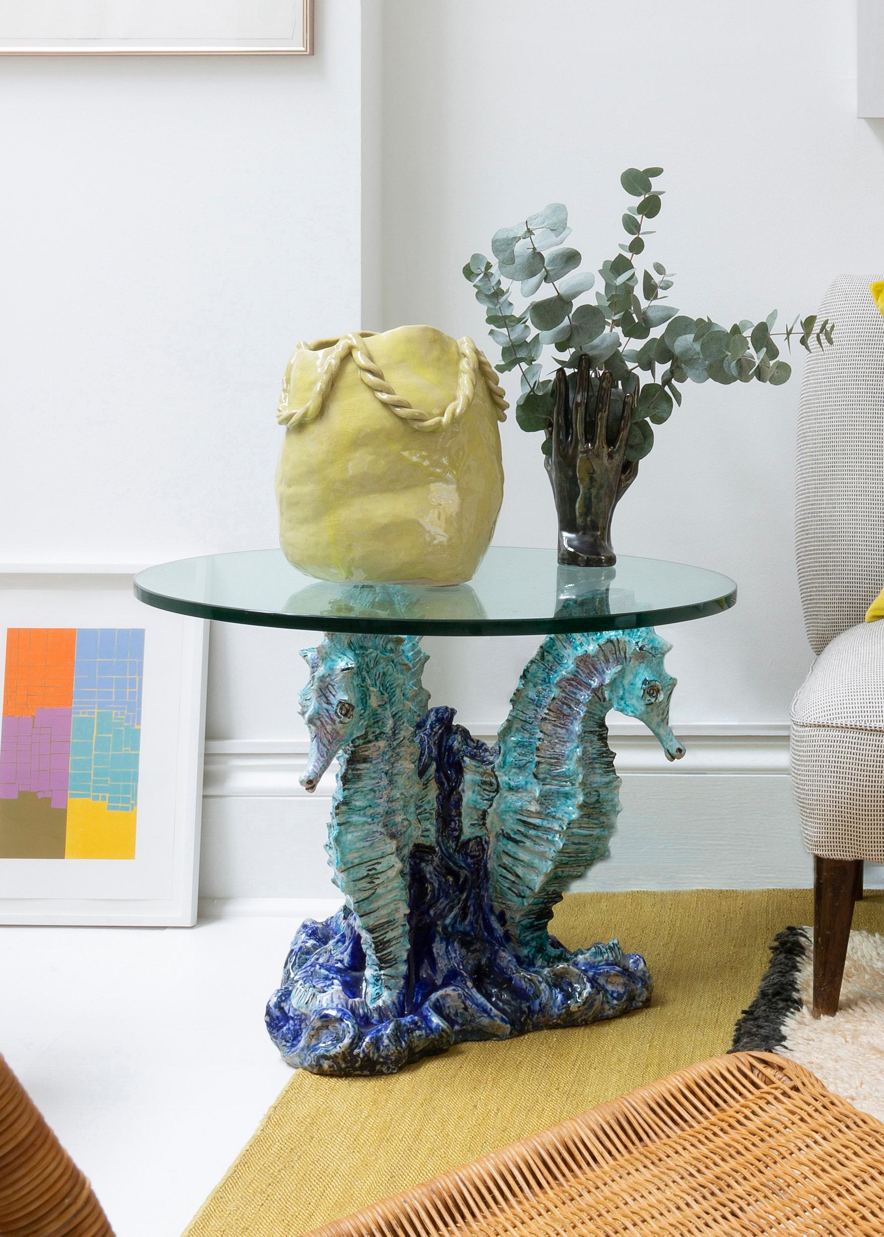 Quirky Italian side table with sculptural ceramic base in the shape of seahorses and a glass top. 1960s.

Dimensions: 50 x 60 x 60 cm.