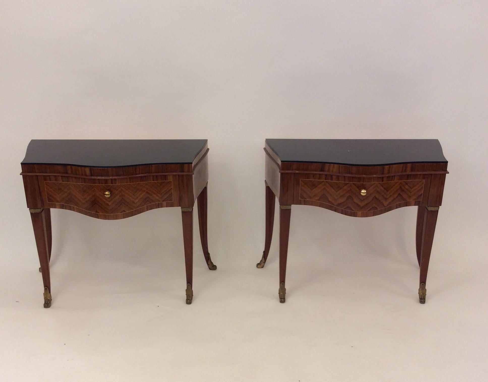 An outstanding pair of hand crafted side tables with drawers, fantastic marquetry made of mahogany, walnut and a mix of  woods. 
Black glass top, brass shoes at the final of the legs.
Attributed to Gio Ponti.