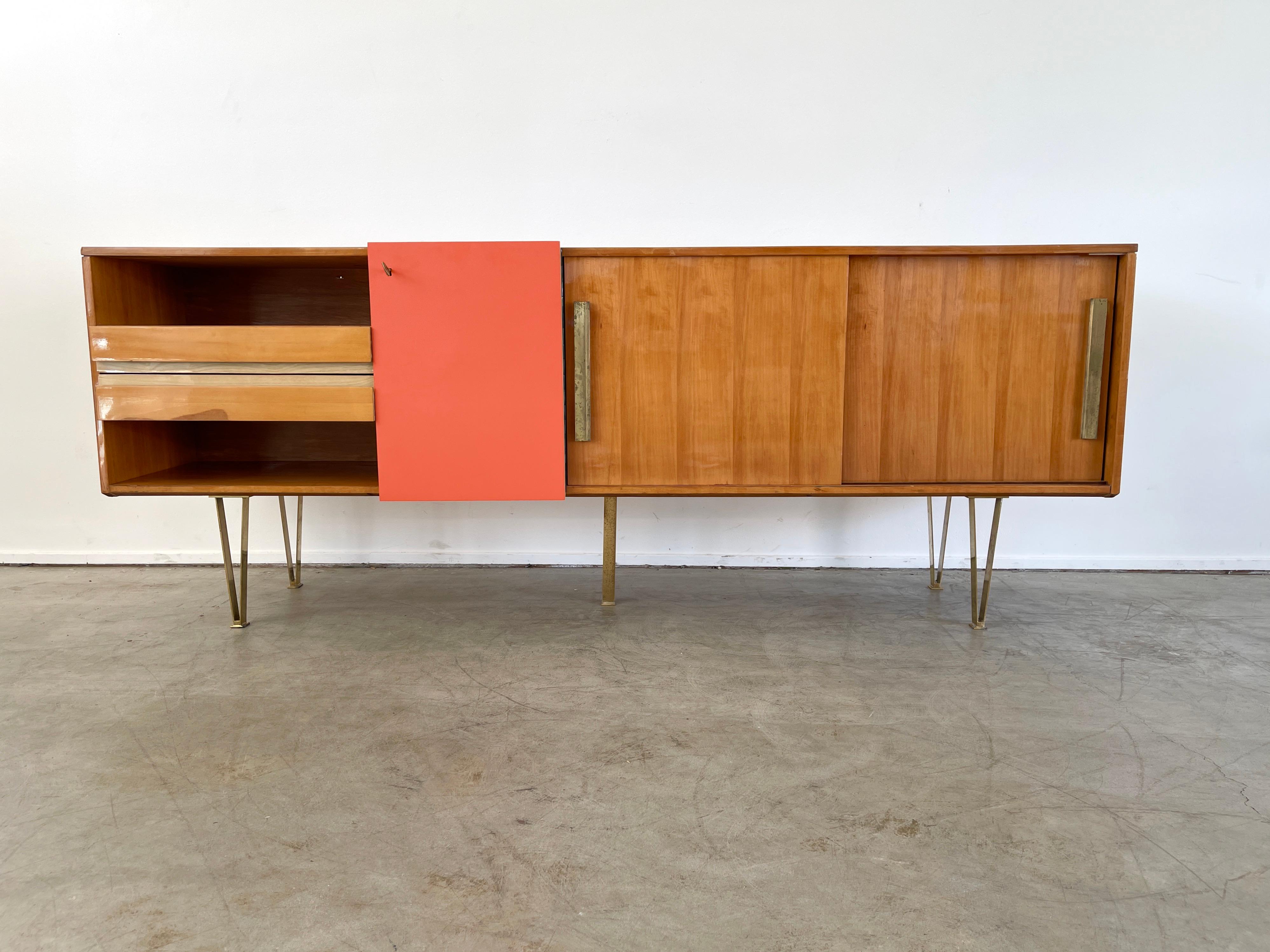 Italian sideboard circa 1960's
Walnut case with red formica door, drawers, and sliding doors 
Brass hairpin legs 
Unique piece and large in scale. 
 