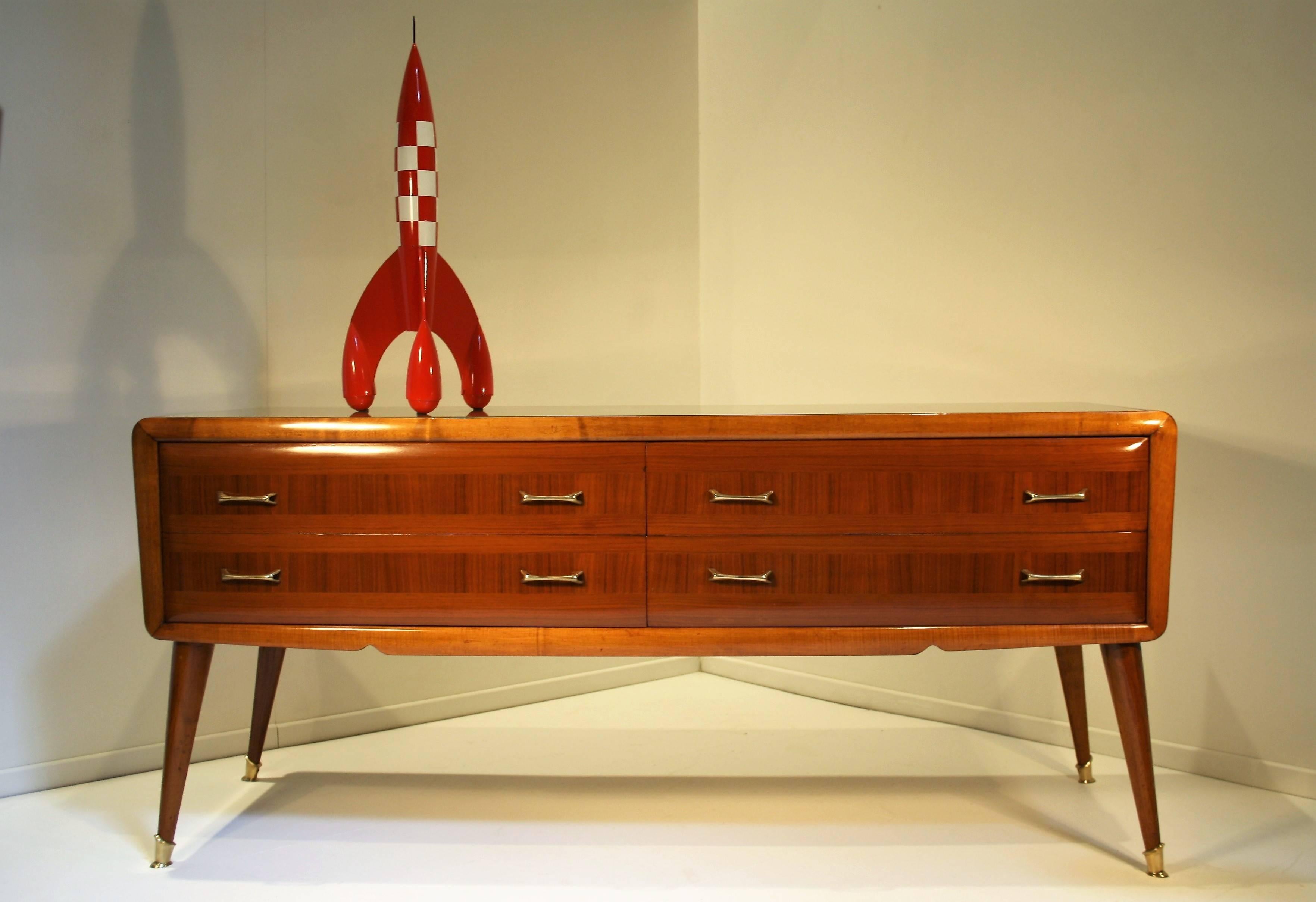 Elegant sideboard by Paolo Buffa standing on four oval conical legs that end in a brass base.
The four drawers have nicely detailed brass handles and the sideboard still has its original polish in very good condition.
The top has a gold tinted