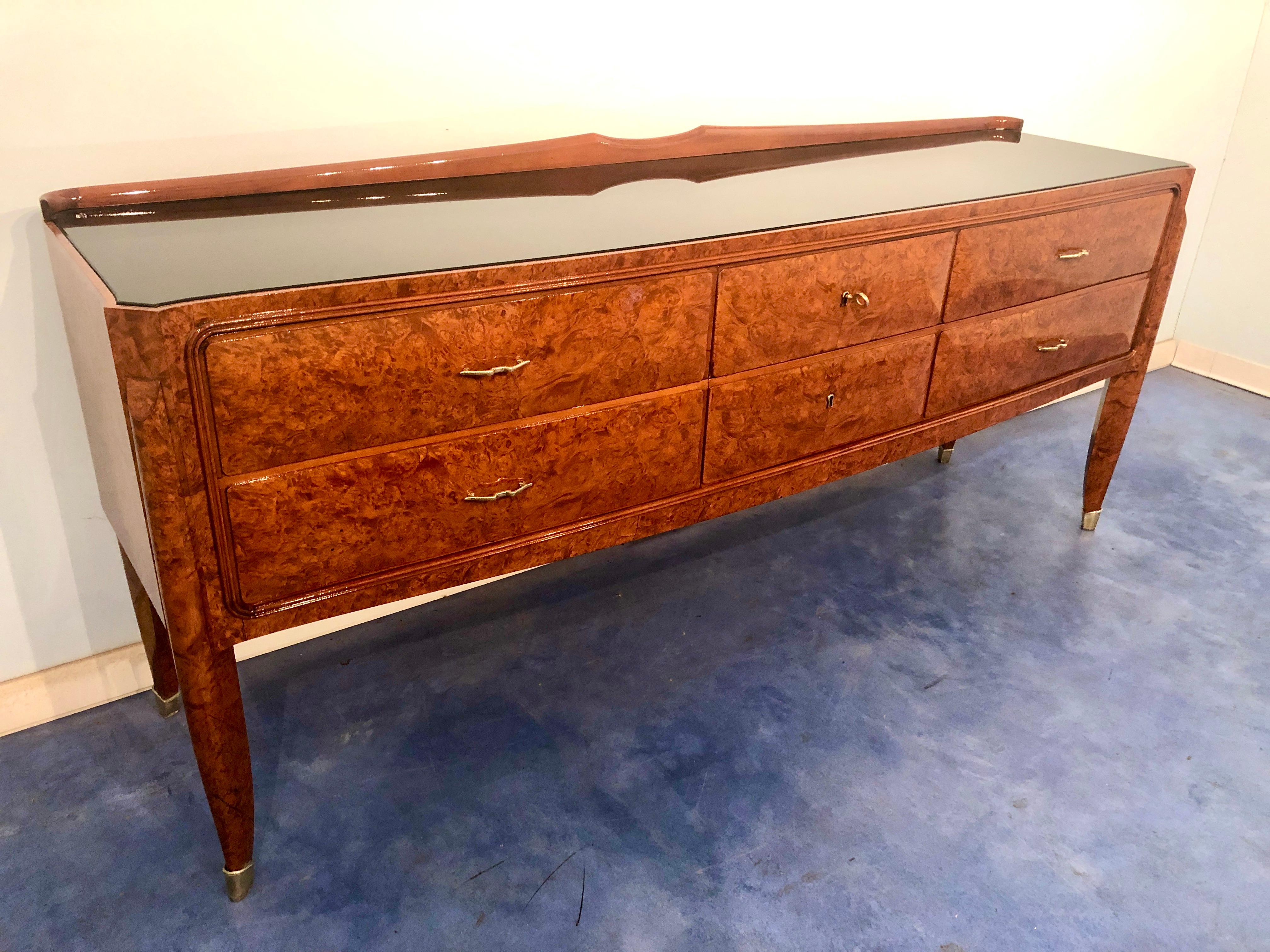 Elegant, height quality sideboard/commode attributed to Paolo Buffa, 1950s.
Made of precious burled amboyna, black glass on top, saber-shaped legs with brass sabot at the ends.
Very good condition completely restored and ready to use.