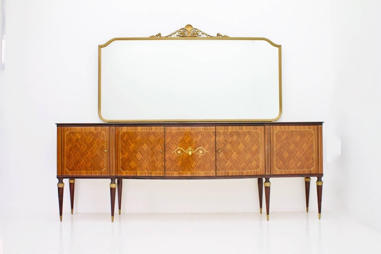 Very nice Italian sideboard with a large mirror. The sideboard was bought in 1959 in Italy. It has a total of five doors and a glass surface which is nicely marbled.
In the front, the wood is very nicely processed. The legs are decorated with