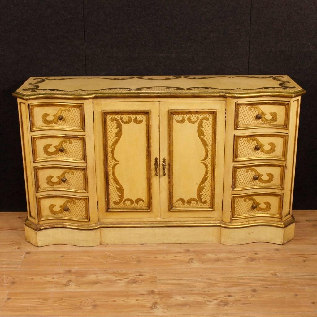 Italian sideboard of the 20th century. Furniture in richly carved, lacquered, gilded and chiselled wood with fabulous decoration. Sideboard with two doors and eight drawers of excellent capacity, complete with a working key. Top in wood also