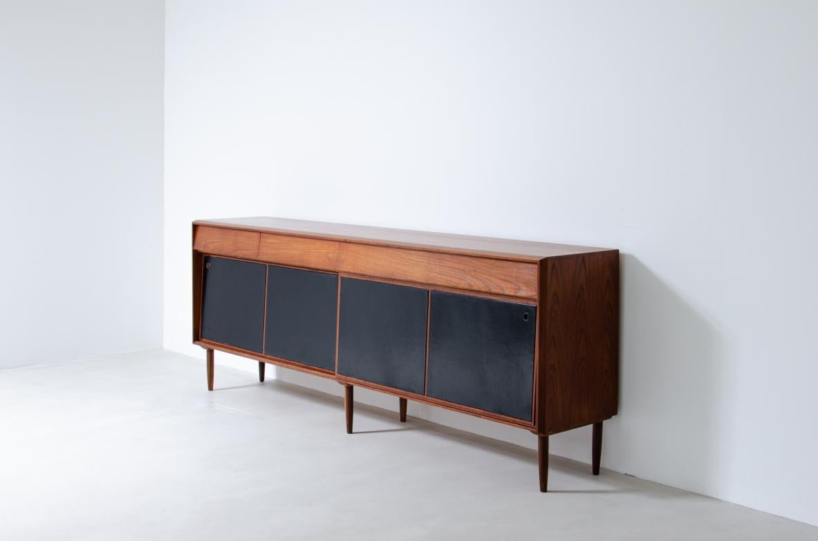 COD-1896
Elegant sideboard in teak wood with drawers and sliding doors covered in black leather.

Italian manufacture, 1960's.