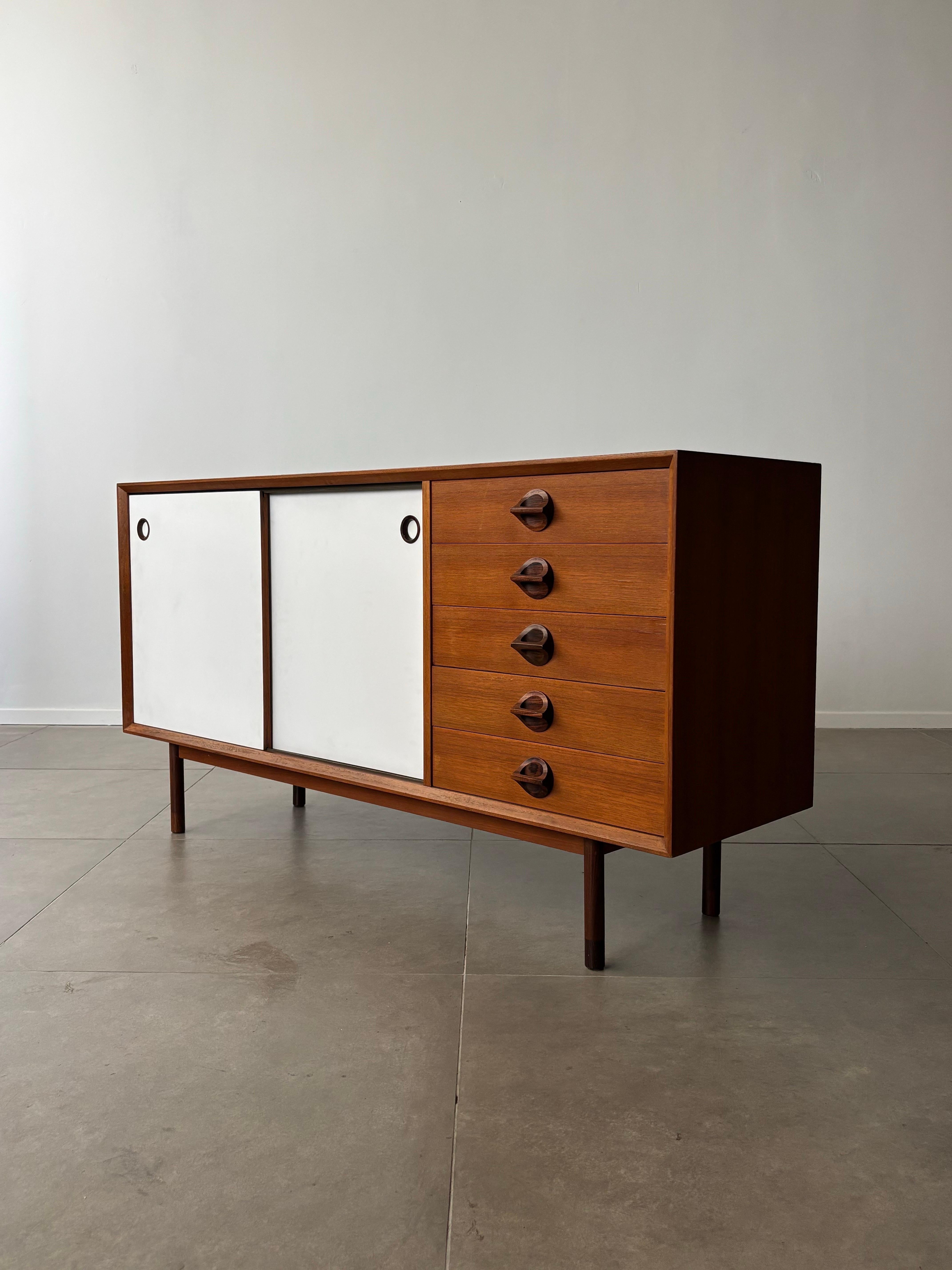 The Italian sideboard “Monika” by George Coslin for Faram, designed in the 1960s, is a stunning example of midcentury craftsmanship and versatility. This beautifully designed piece features two sliding doors with a reversible finish—one side in