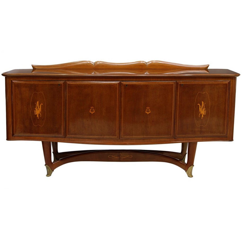 An Italian Mid-Century Modern mahogany sideboard with lighted central bar shelf circa 1950s, attributed to Vittorio Dassi (1893-1973). The piece features a insert glass top with shaped splash back over four serpentine doors. The center doors opening