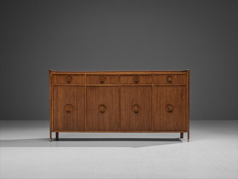 Sideboard, oak, brass, Italy, 1960s. 

This partially carved sideboard features a clear rhythm and flow that has been achieved through a thoughtful layout that is perfectly balanced. The whole unit is executed in warm oak. The doors embody elegant