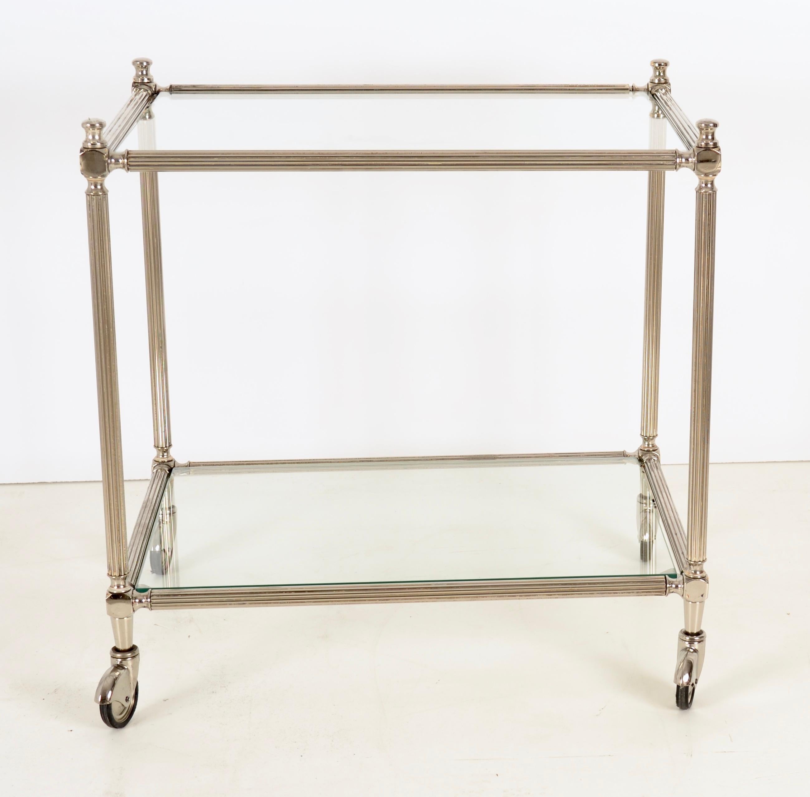 Glamorous cocktail cart, made in Italy, featuring fluted column legs, glass top and lower glass shelf. The silver finished metal has been newly polished and lacquered. The original swiveling wheels have been polished and are in fine working