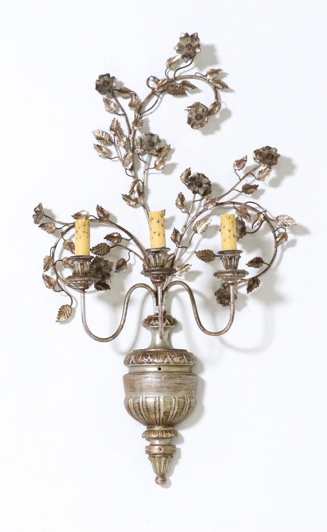Gorgeous, Italian 1950s silvered iron and wood pair of sconces.

Each sconce consists of an urn-shaped silver-leafed wood base with a spray of iron branches and carved wood flowers. 

The sconces are wired and in working condition, they require