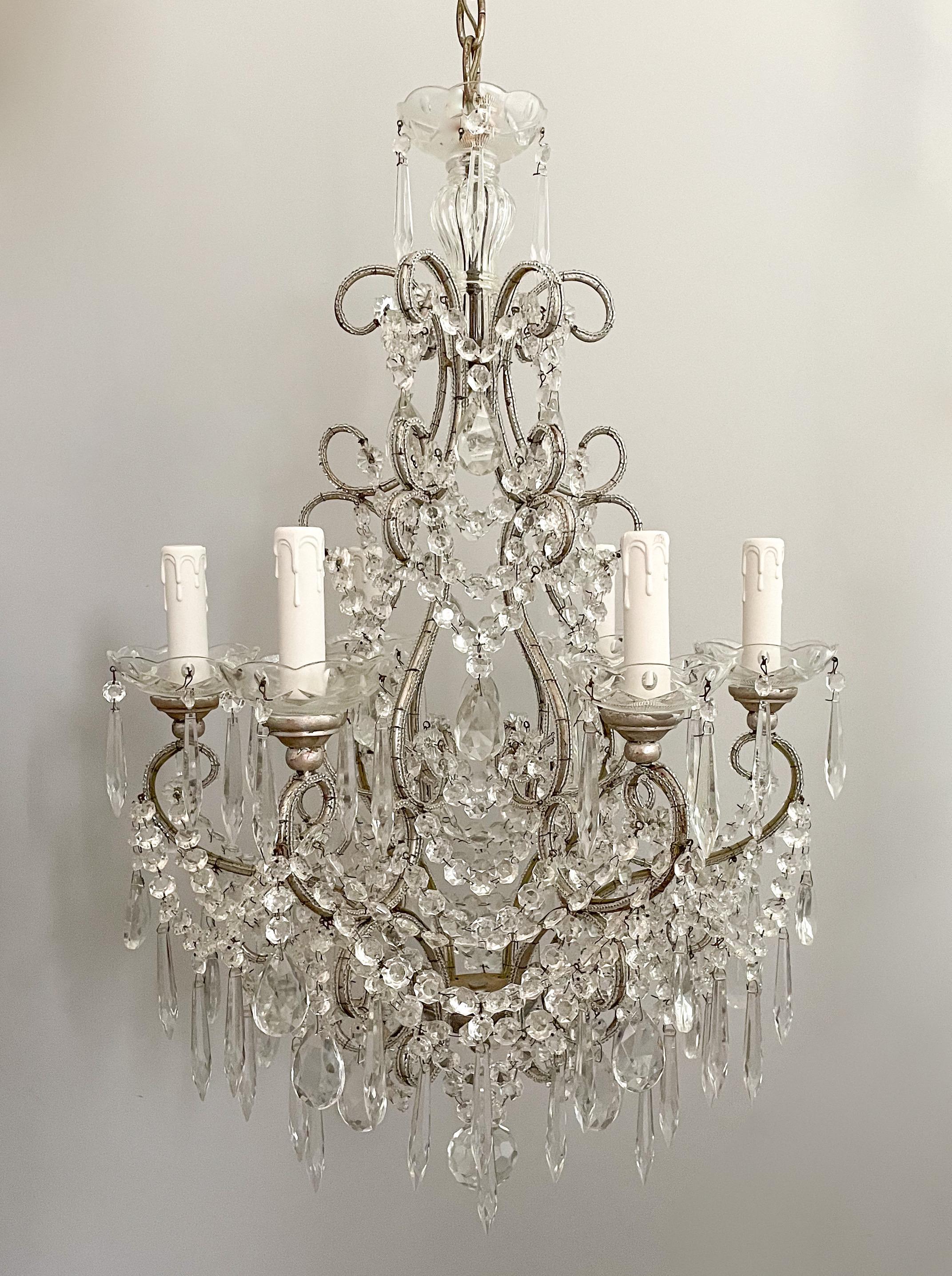 Beautiful, Italian silvered-iron and crystal beaded chandelier.

The chandelier consists of a scrolled, silver-leafed frame outlined with small glass beads. It is decorated with an abundance faceted beads swags and prisms. 

The chandelier is