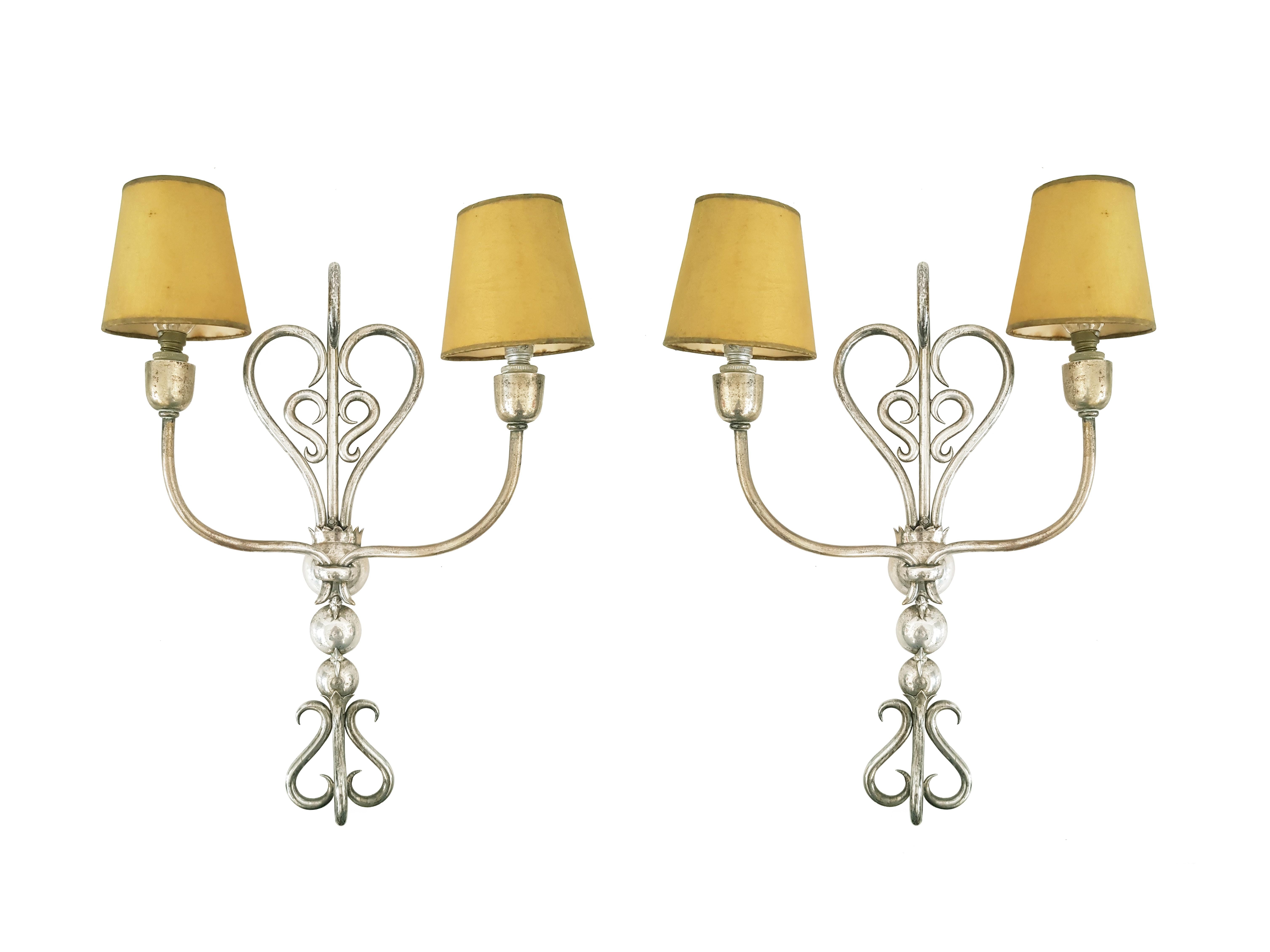 This elegant pair of wall lamp was hand made in Italy around 1930s. The structure is made with a brass rod folded and welded to form a sinuous and elegant decorative motif of volutes.
Each lamp is equipped with 2 small lamp holders (E14