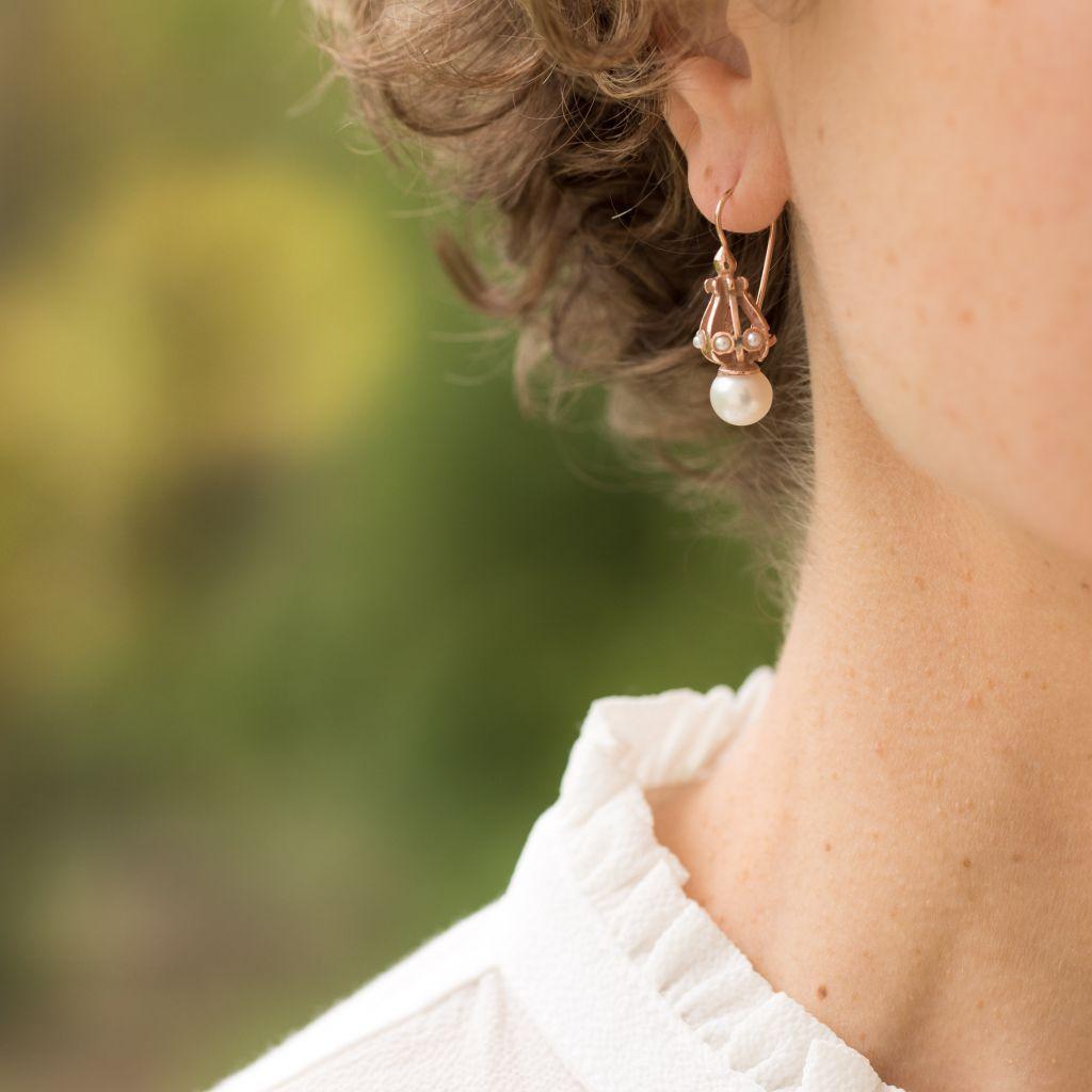 For pierced ears.
Pair of earrings in sterling silver, and rose gold. 
Lever- back, they are formed of a domed openwork pattern set with small white glass pearls which supports a larger white glass pearl.
The hanging system is a swan neck with