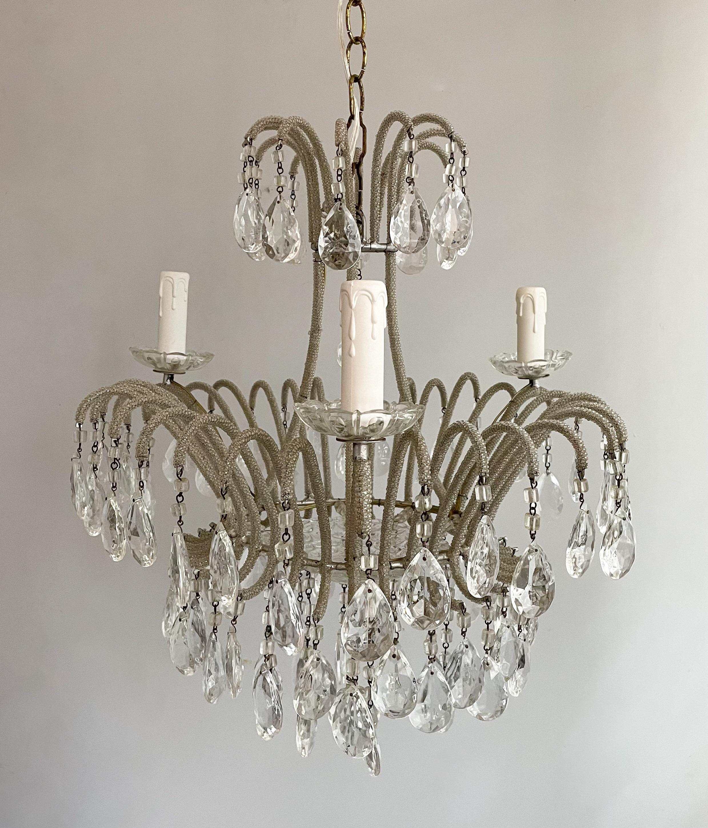 Wonderful, Italian 1940s silvered-iron crystal beaded chandelier. 

The chandelier consists of scrolled iron frame wrapped in tiny silvered glass beads and decorated with clear faceted prisms hanging from macaroni glass beads. There’s a decorative