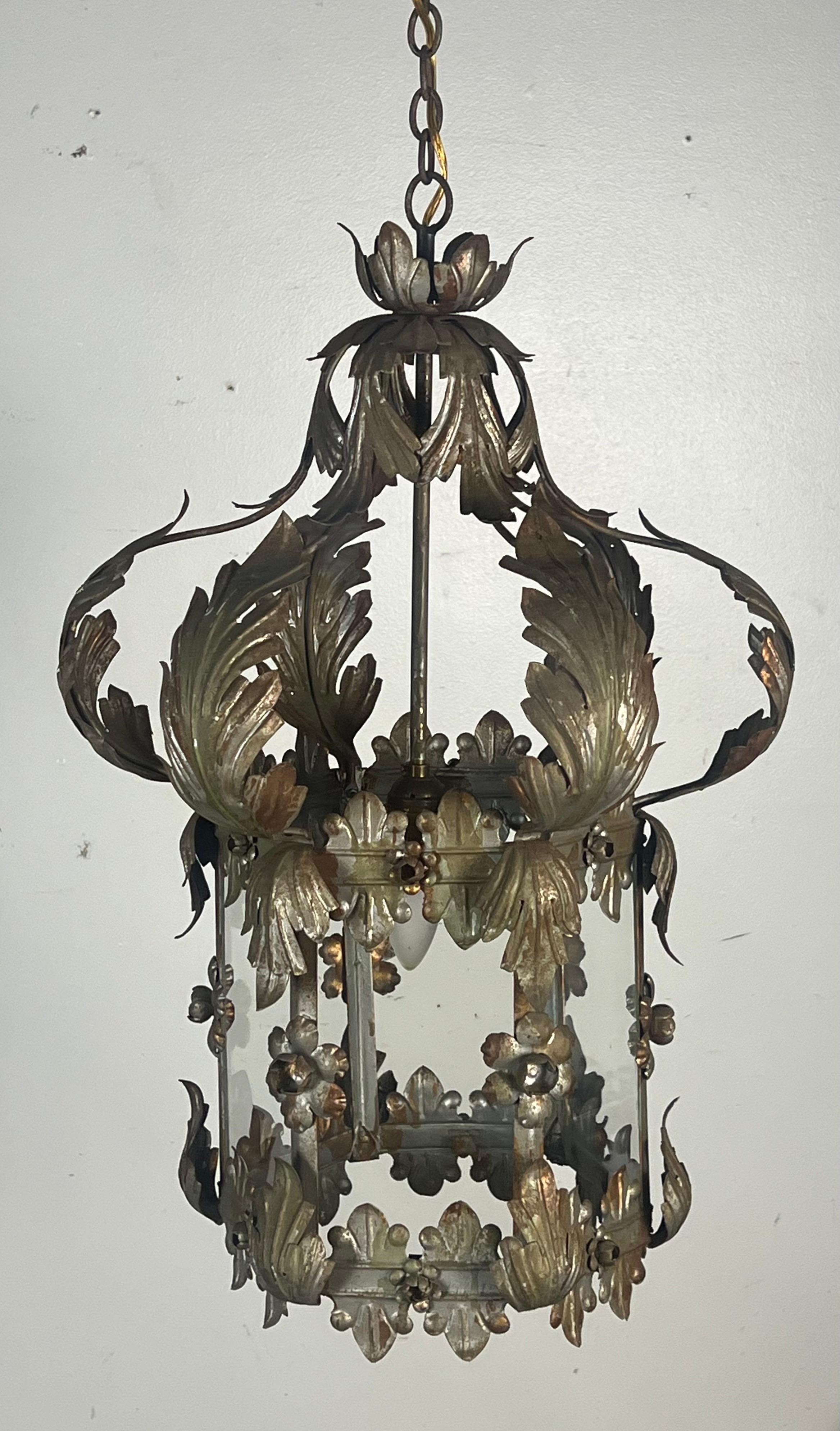 Lanterna dalla forma cilindrica centrale con la parte superiore a forma di corona.  La lanterna è decorata con numerose foglie d'acanto e motivi floreali.  Le foglie sono curve e dettagliate.

Il metallo presenta una patina con resti d'argento. 