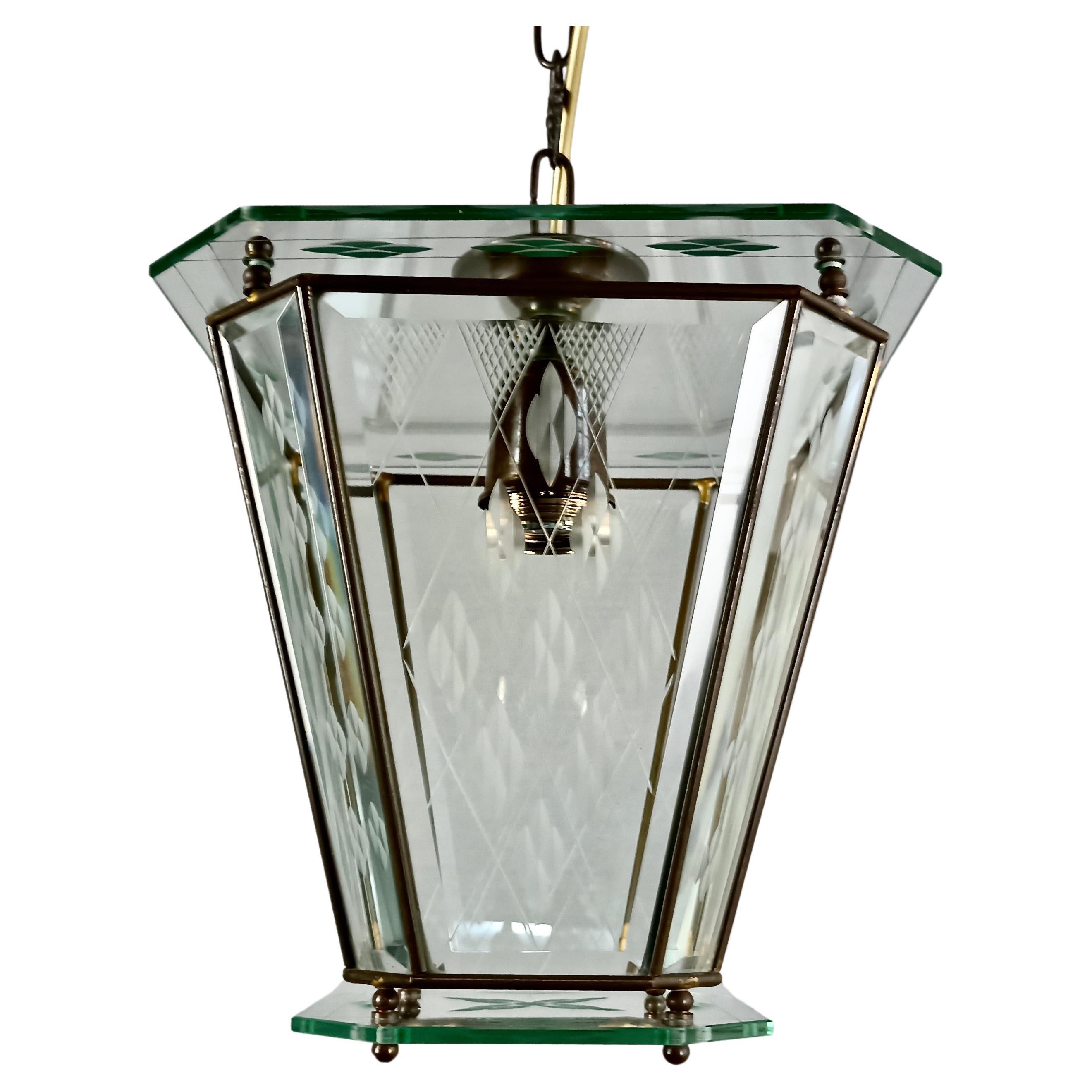 Beautiful Italian single-light 1950s lantern with shaped clear glass panes, grounded at the edges and engraved with nice decorative geometric patterns.
The lamp has a flared brass frame that holds mounted in the central part four trapezoidal-shaped