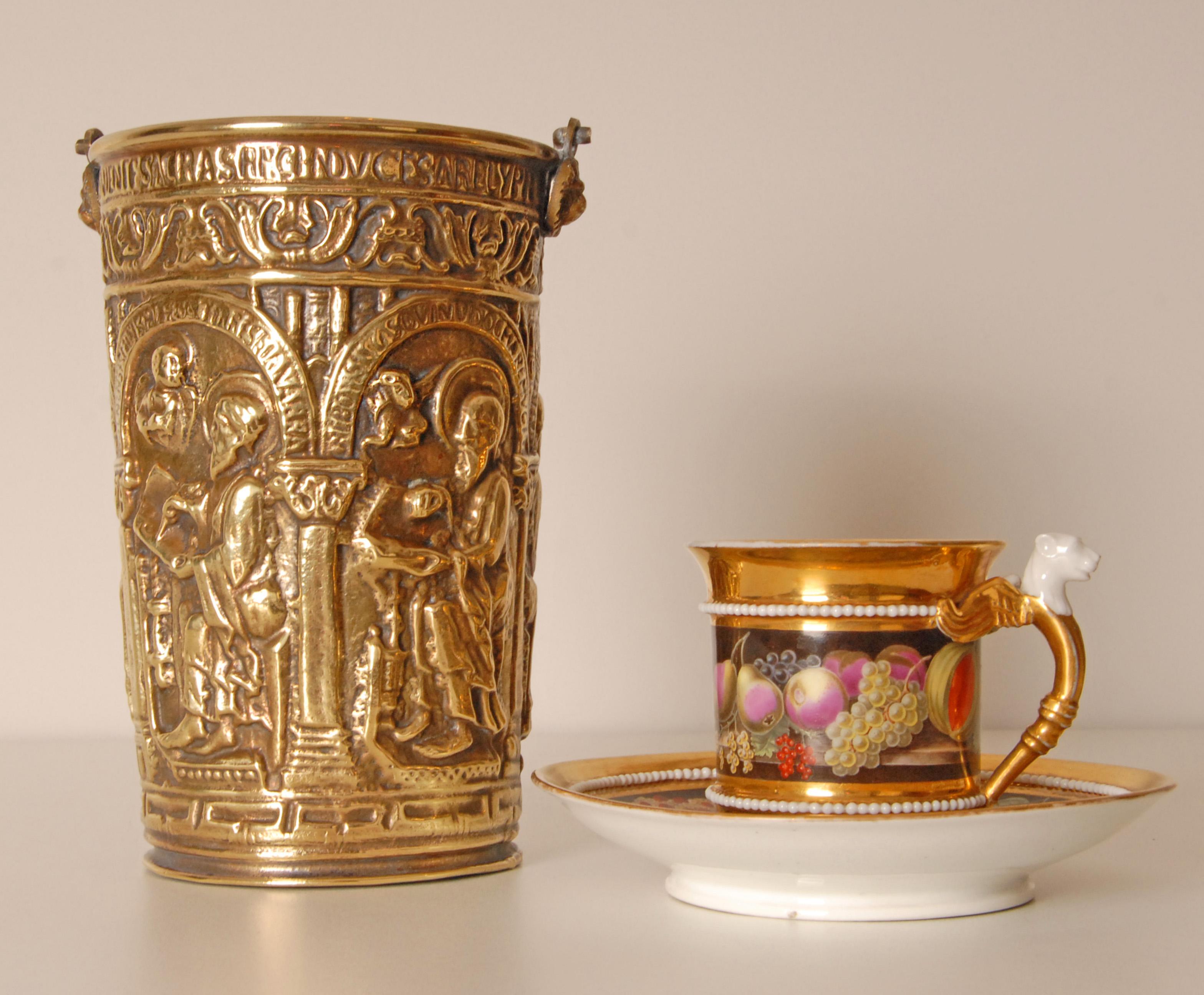 Situla italiana, secchio d'acqua in agrifoglio.
La maniglia è sostenuta da due leoni.
La situla che raffigura  5 colonne collegate da un porticato di 5 archi. 
Sopra gli archi vediamo una fascia di fogliame che scorre e sotto il bordo superiore una