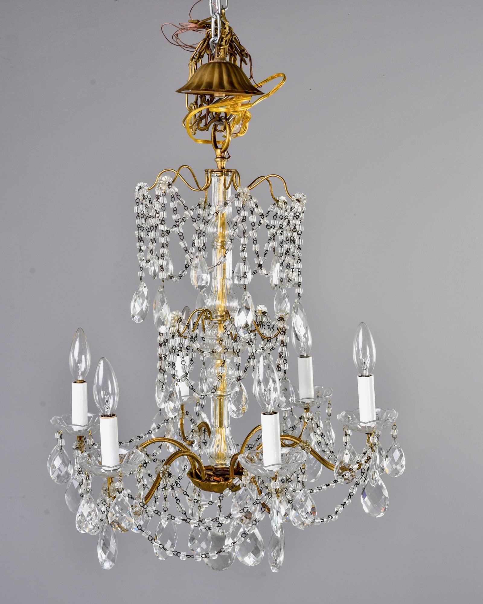 Italian chandelier has six candle style lights with candelabrum sized sockets, faceted tear drop shaped crystals and beaded swag, circa 1930s. Unknown maker. Rewired for US electrical standards.
 