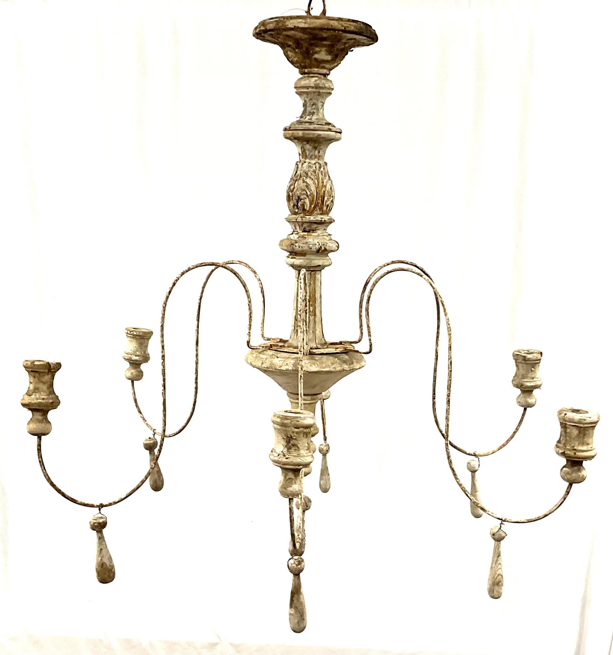 An Italian six arm chandelier comprised of antique elements. Aged patina and neutral colors. Scrolling wrought iron arms with carved and turned grey painted wood baluster, gilt wood tassel and bell hanging decoration, all now with a wonderful aged