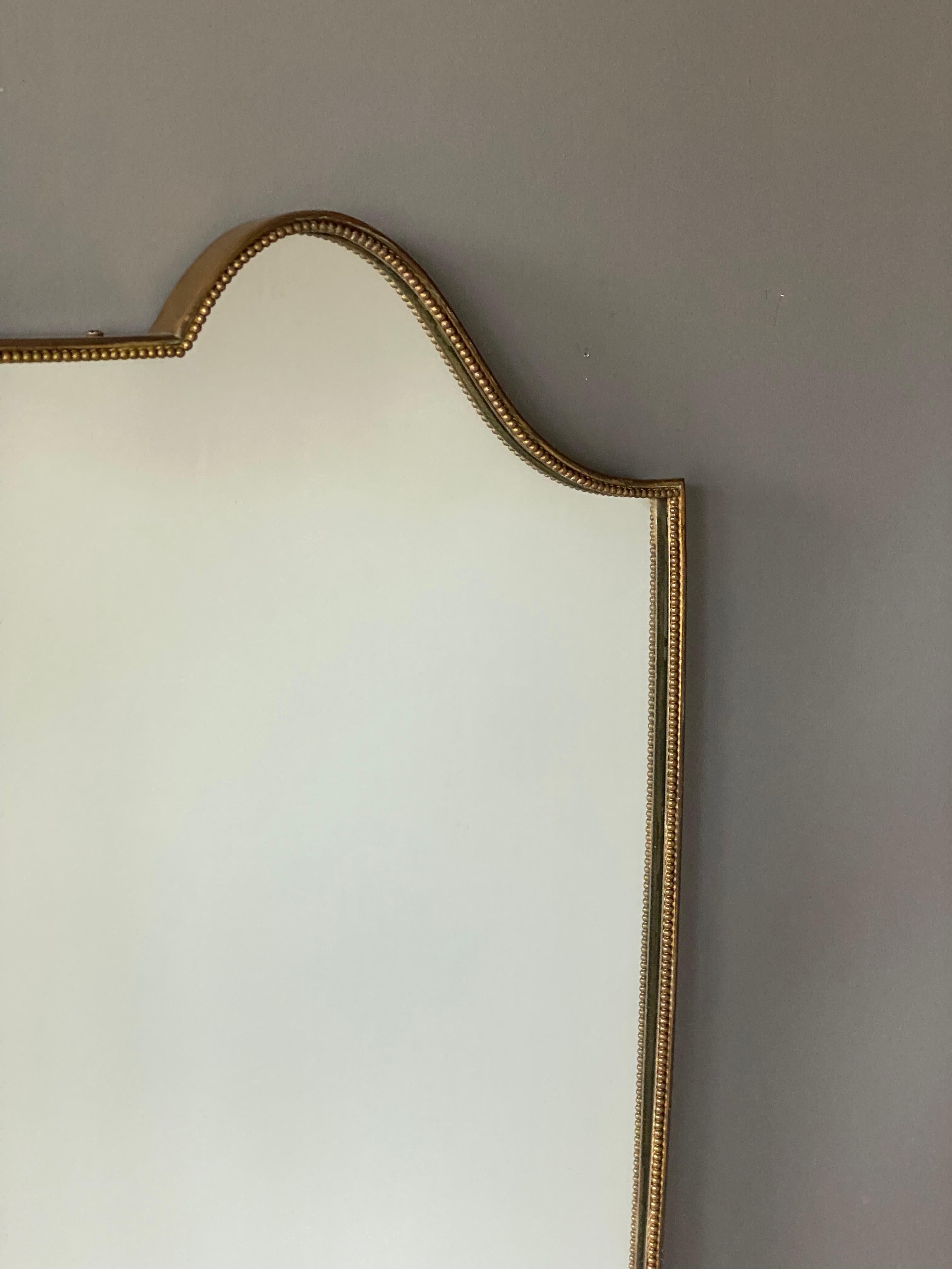 A sizable organic wall mirror, produced in Italy, 1940s. Organically cut mirror glass is framed in brass. Features fine ornamentation.

Other designers of the period include Gio Ponti, Fontana Arte, Max Ingrand, Franco Albini, and Josef Frank.