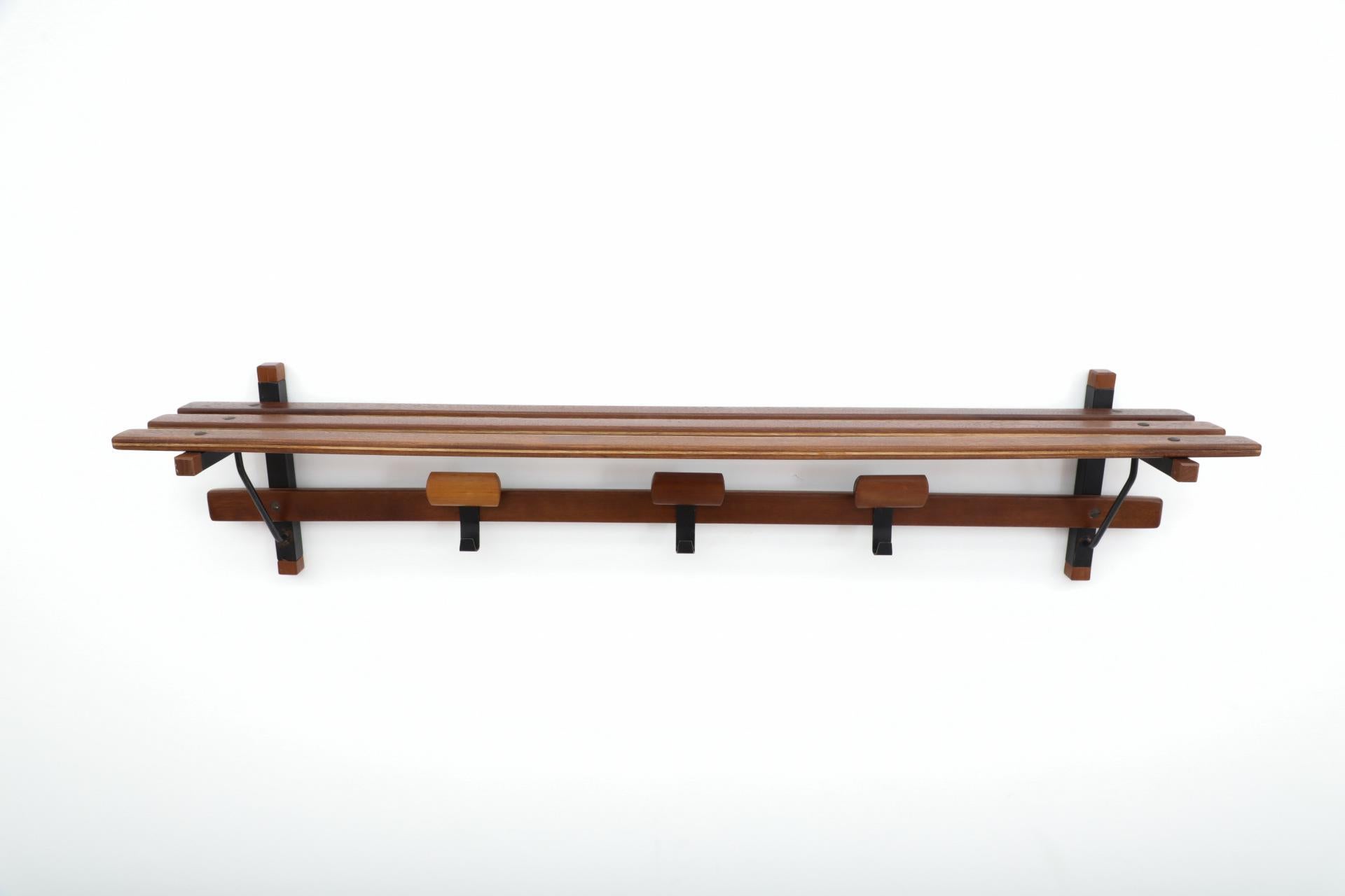 Long slatted teak and black enameled metal wall mount coat rack with movable wood hooks and elegant rounded multi-wood bars. In lightly refinished condition, with some wear to metal and scratches on wood. Wear is consistent with age and use. Other