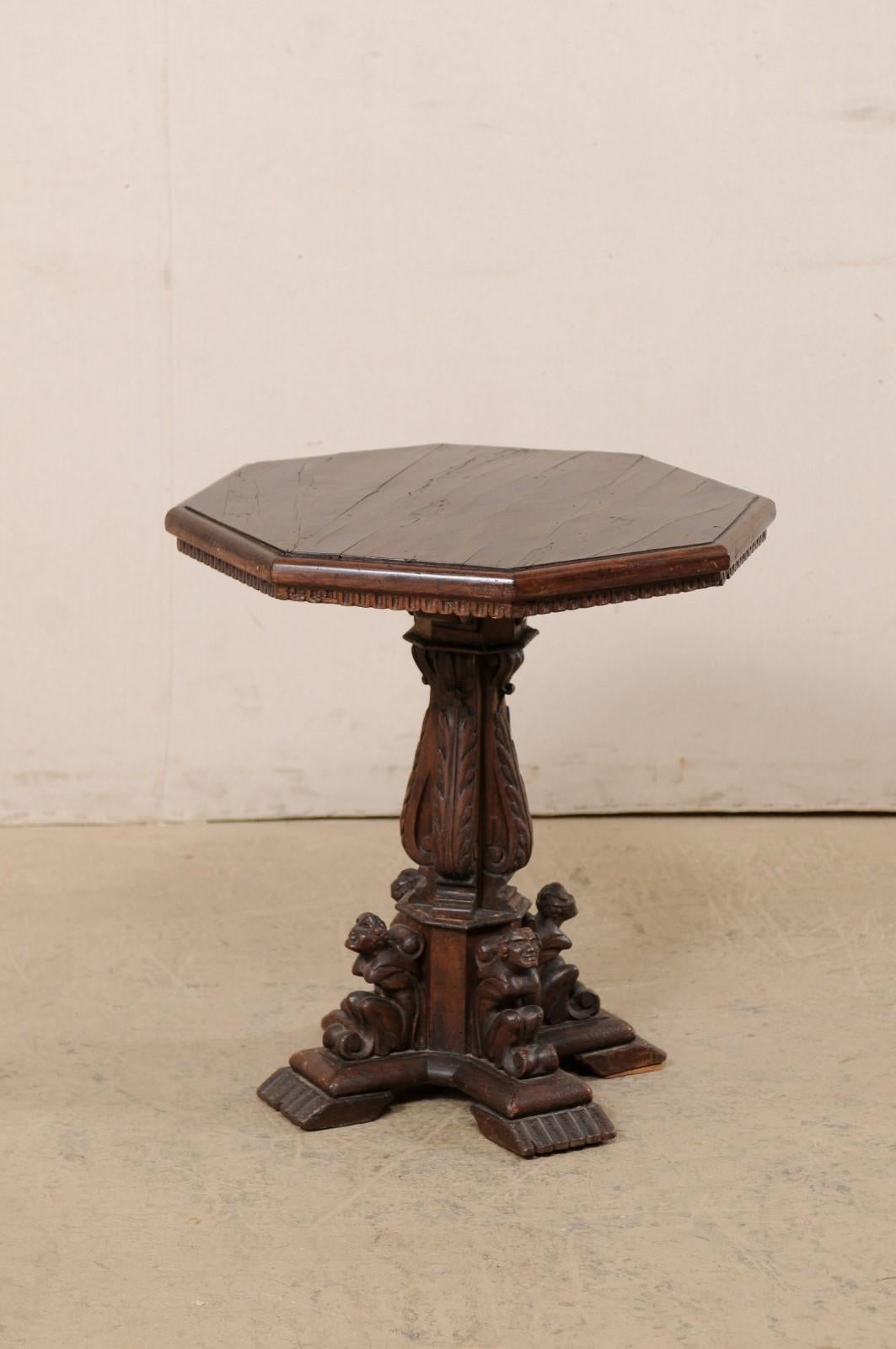 An Italian wooden occasional table, with highly carved acanthus and figural motif pedestal base, from the early 19th century. This antique table from Italy features an octagonal-shaped top which rests above an elaborately decorated pedestal, wrapped