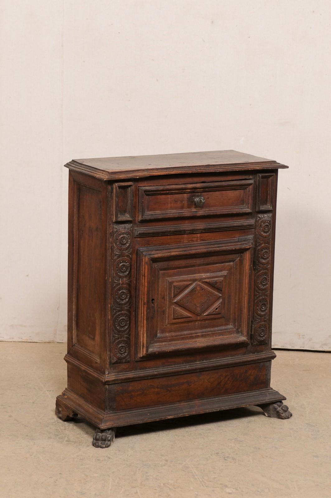 A Italian smaller-sized carved walnut commode, with single drawer and door, from the turn of the 17th to 18th century. This antique cabinet from Italy has has a rectangular-shaped top, with graduated step down edges, which rests atop a nicely carved