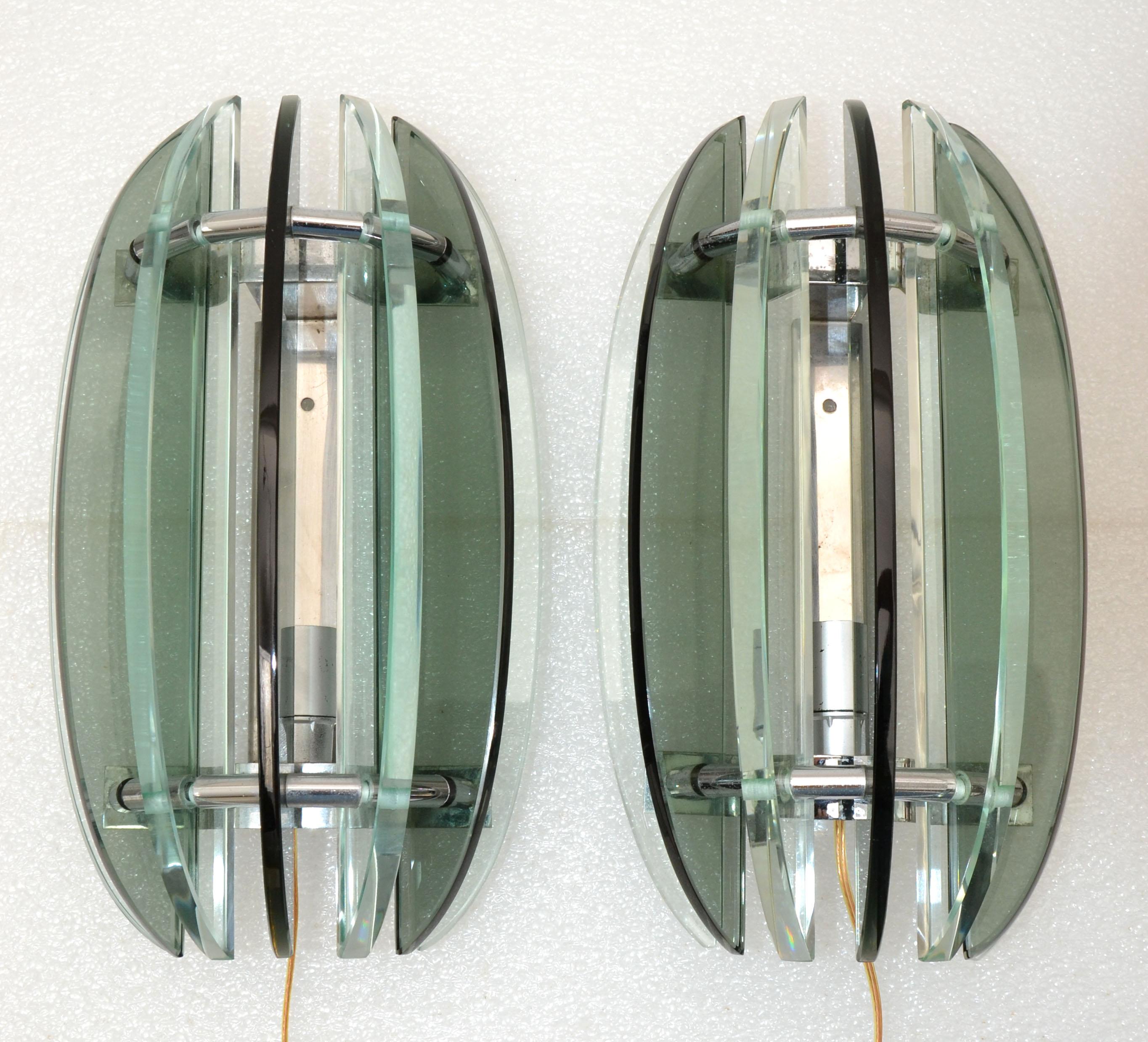 Pair of Italian sconces stamped Veca. Smoke and clear green glass.
Featuring seven alternating pieces of glass on a chrome base.
US rewired and each sconce takes a max 60 watts candelabra bulb or LED.
Have a look on our impressive collection of