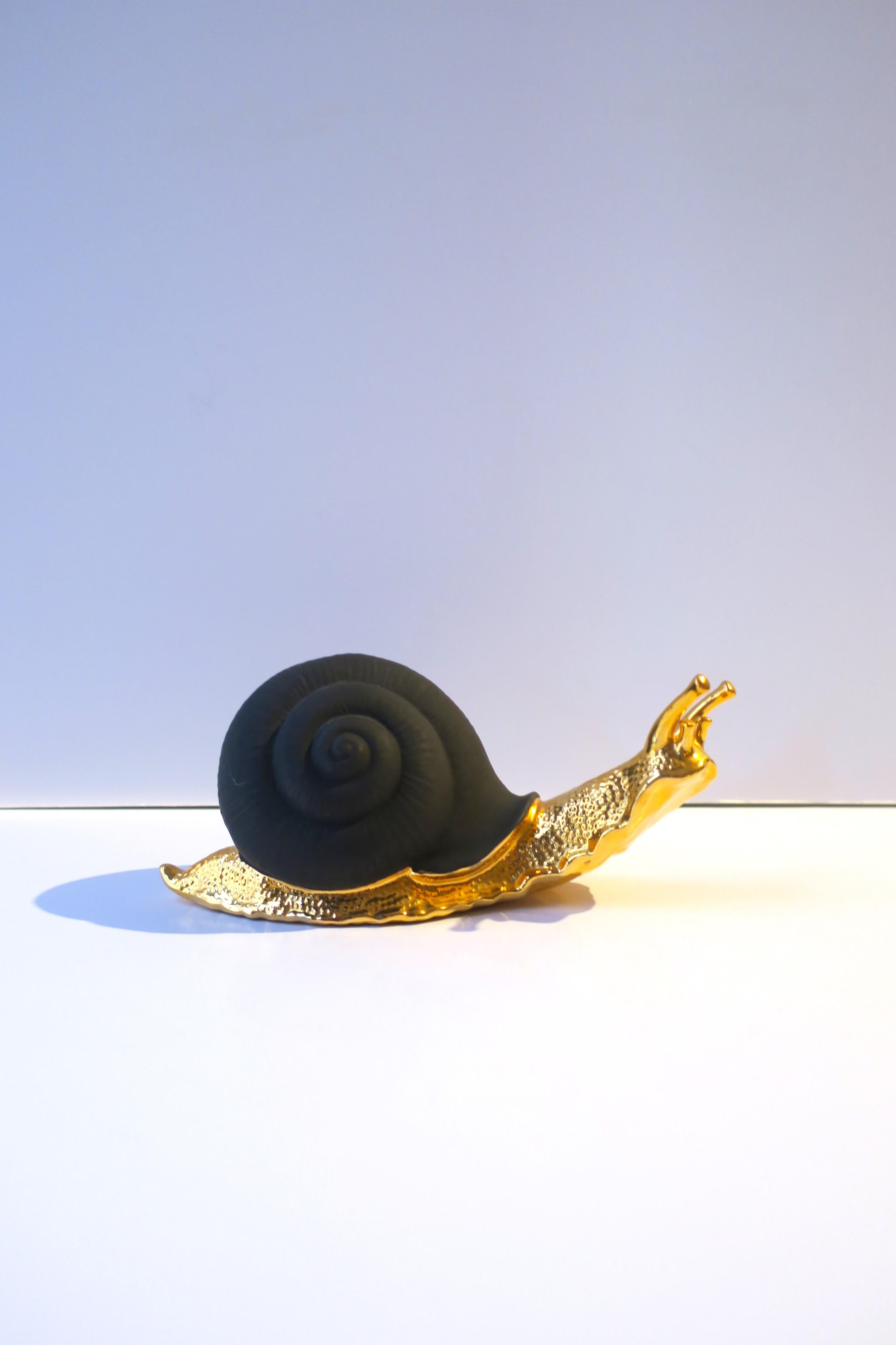 An Italian black basalt porcelain and gold snail sculpture hand-made by S. Puccini, circa late-20th century, Italy. A hand-made piece of matte black porcelain and shiny bright gold enamel, a beautiful combination. Piece could work well on cocktail