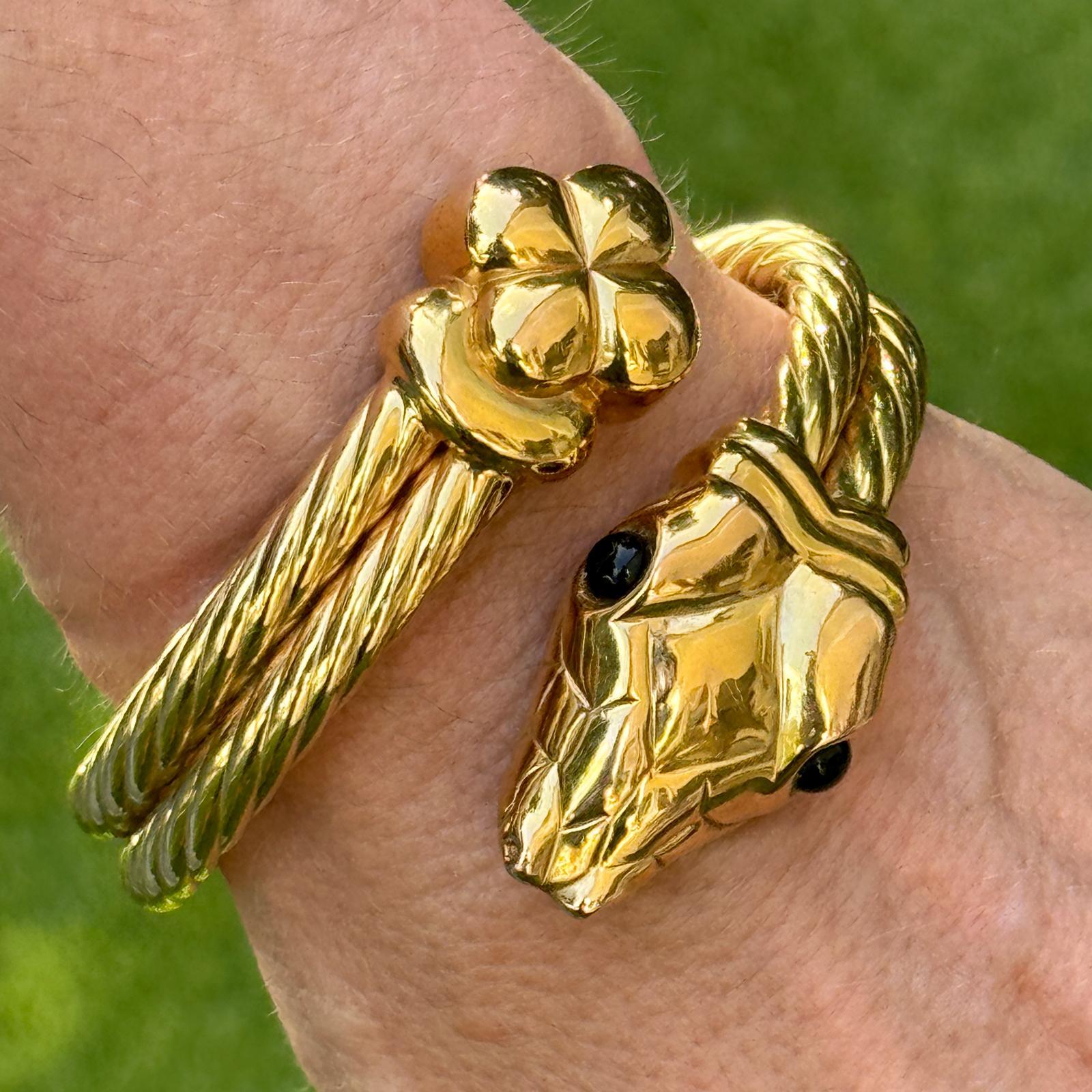 Dieser kühne und skulpturale italienische Armreif aus 14-karätigem Gelbgold ist als zweireihiger Bypass-Armreif mit Scharnieren gestaltet und gipfelt in einem detailreichen Schlangenkopf. Der Schlangenkopf ist mit schwarzen Onyxaugen verziert, die