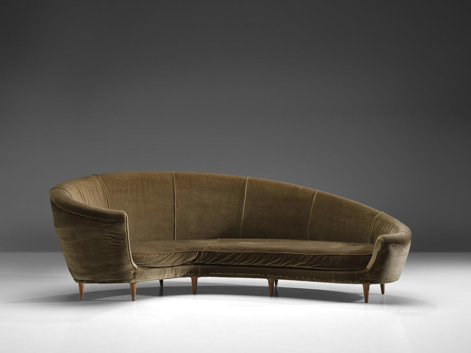 Sofa, green velvet fabric, wood, Italy, 1950s.

This dynamic sofa features in a-symmetrical back that is higher on the left side and slowly slopes towards much lower end on the right side. The six tapered delicate legs are executed in blond wood